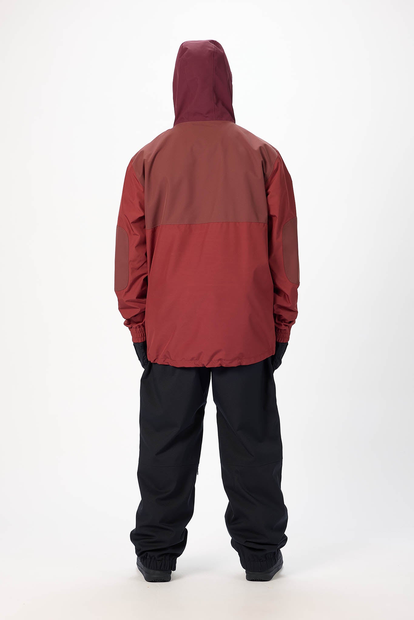 Person wearing a two-tone red and brown jacket with black pants on a white background