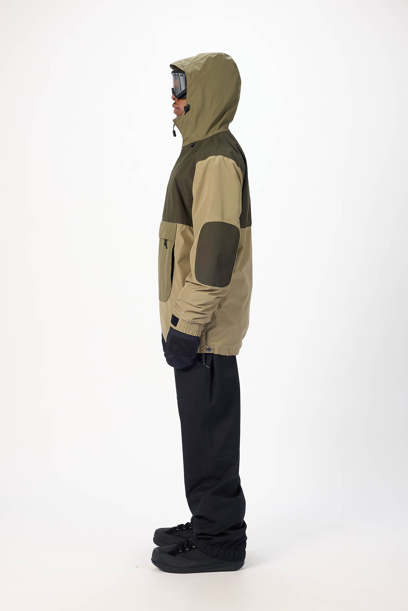 Person wearing a two-tone jacket with green and beige sections on a white background
