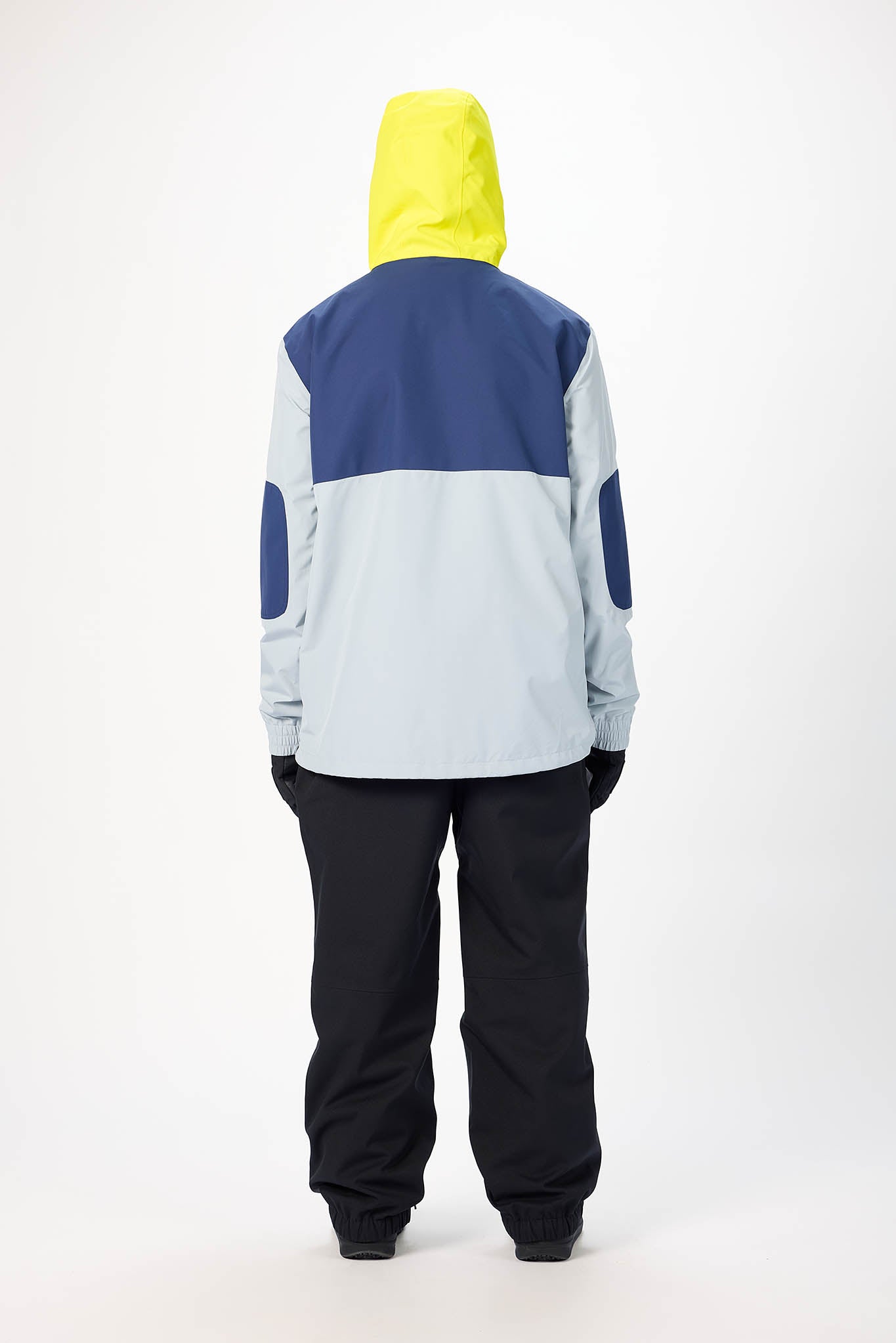 Person wearing a colorful snowboarding jacket and pants on a white background