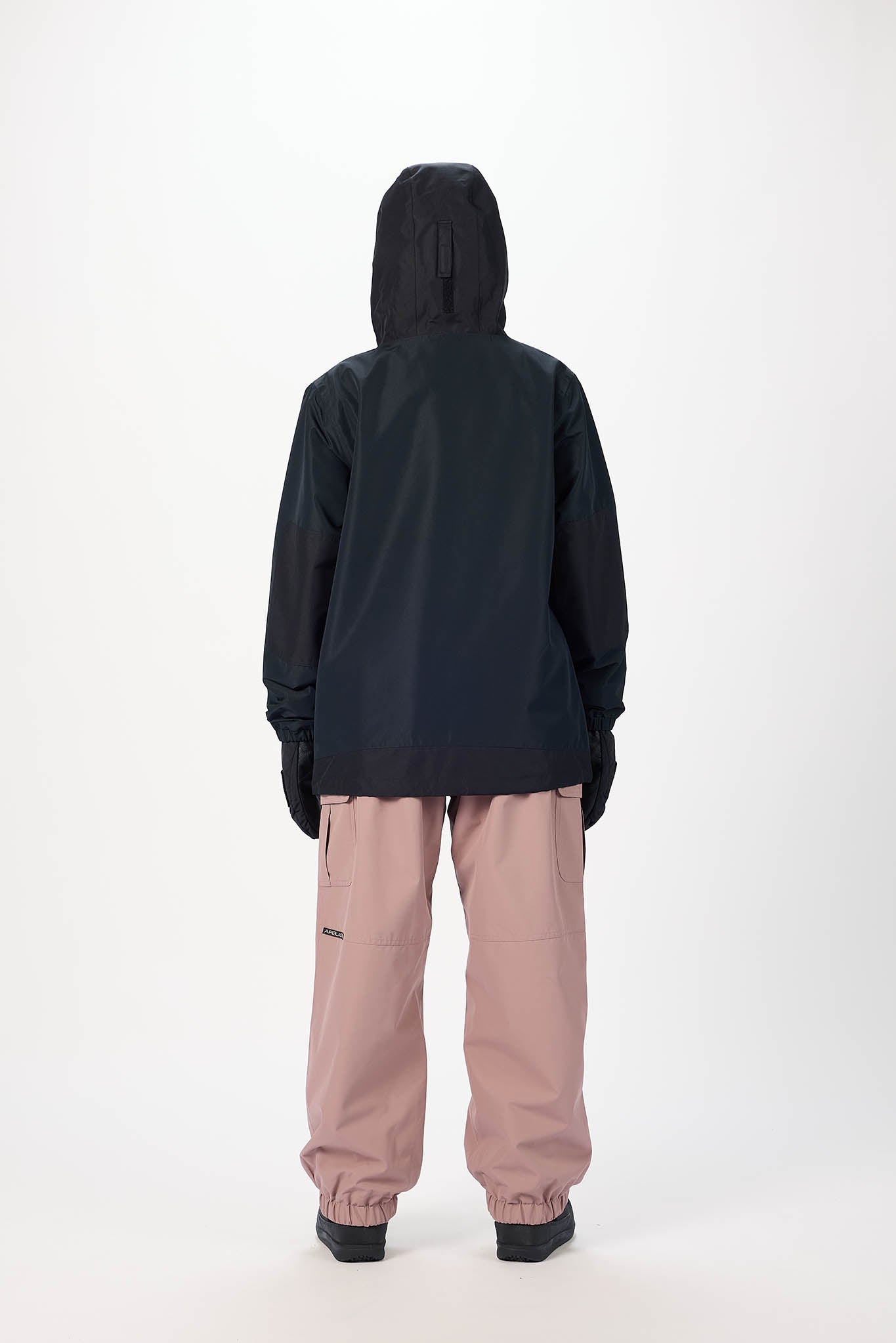 Person wearing a black jacket and pink pants on a white background
