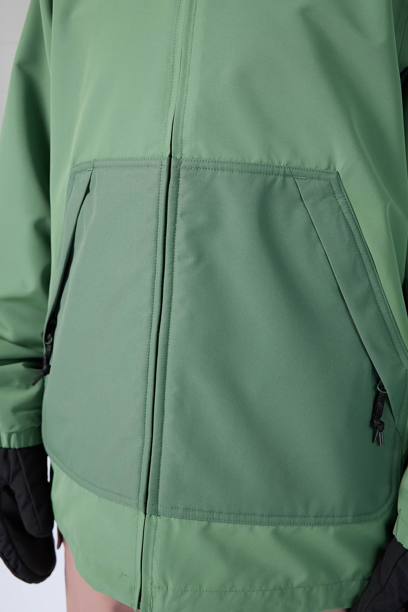 Green jacket with a close-up of the front pocket and zipper