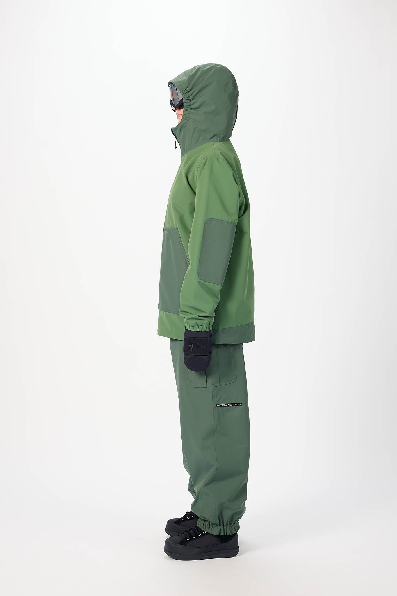 Person wearing a green raincoat and pants on a white background