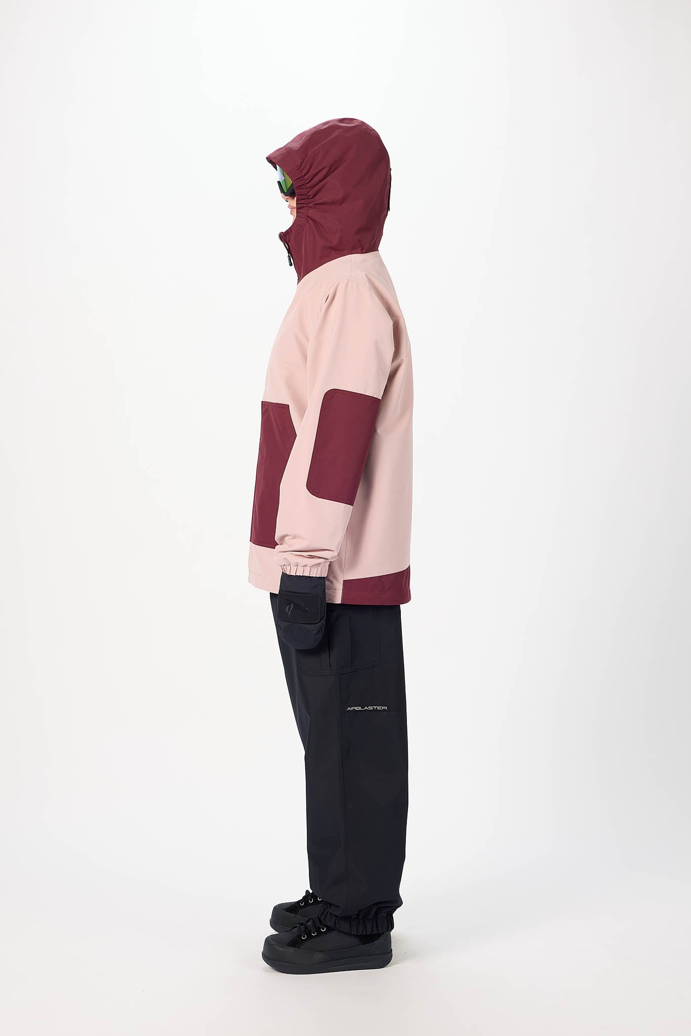 Person wearing a pink and maroon hoodie with black pants on a white background