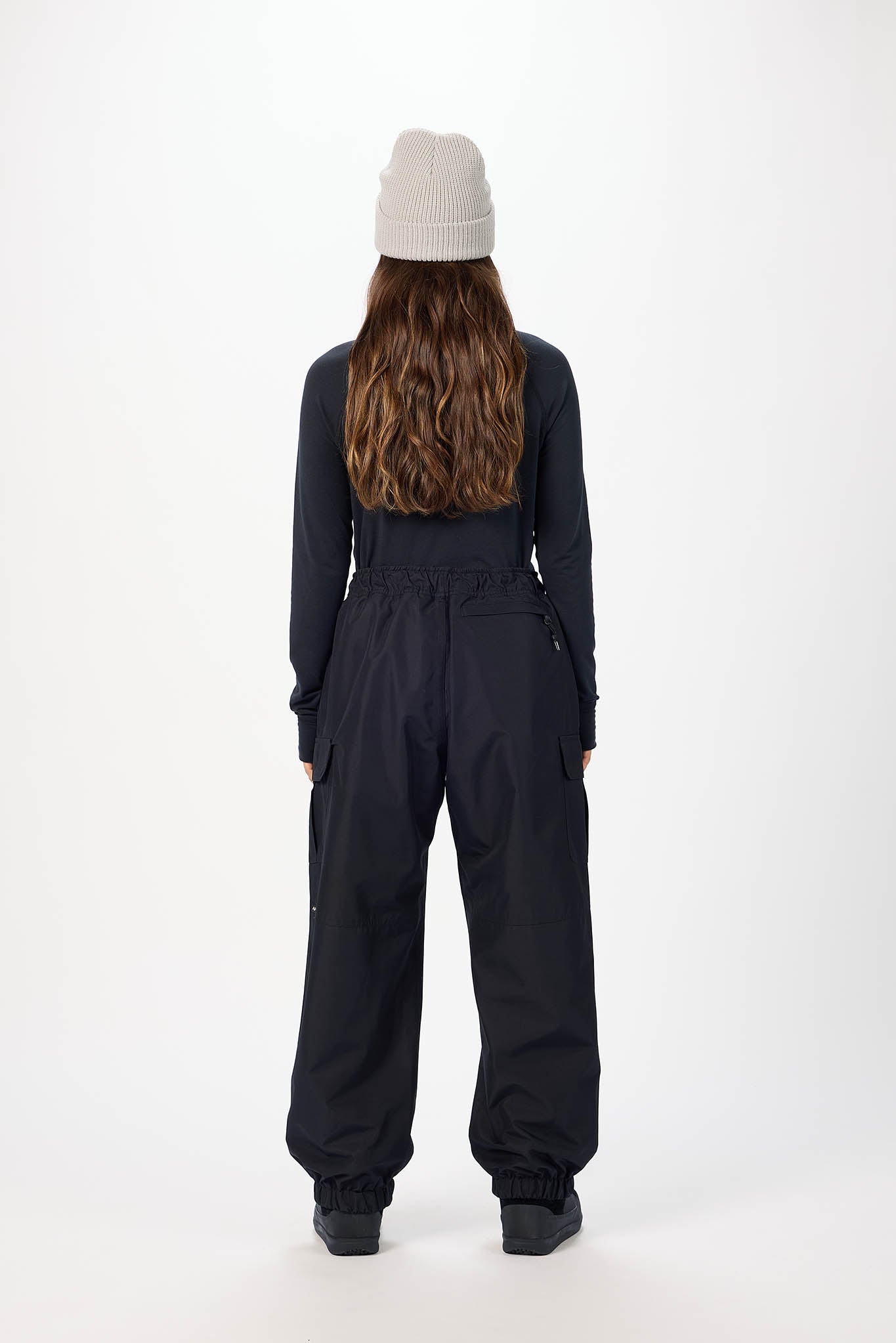 Person wearing a black snowsuit and beige beanie on a white background
