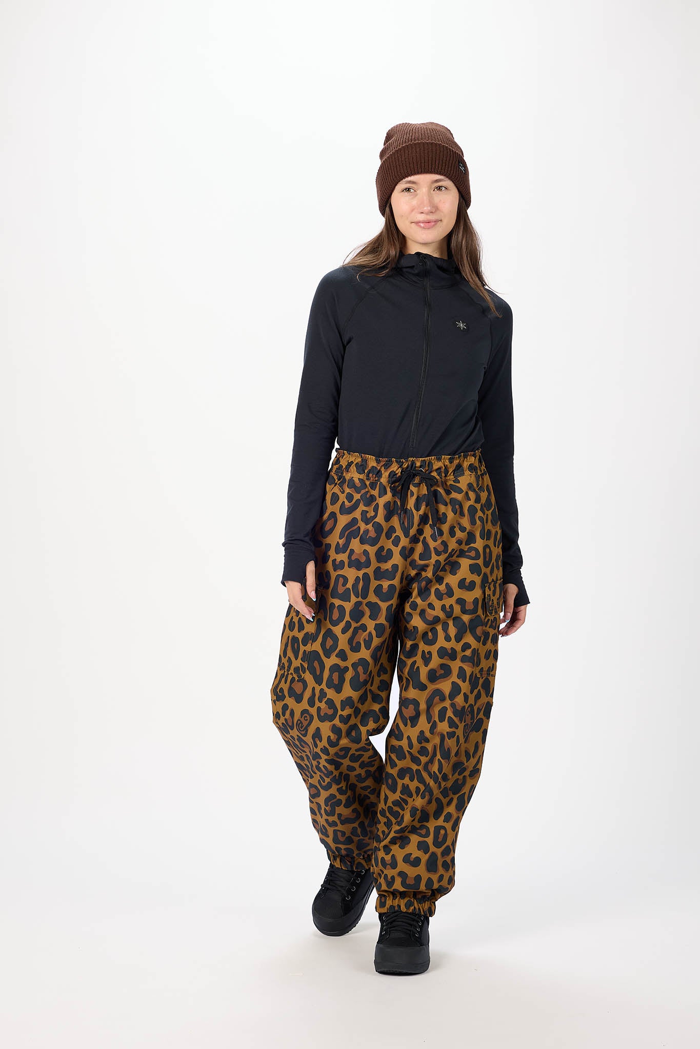 Person wearing a black jacket and leopard print pants on a white background