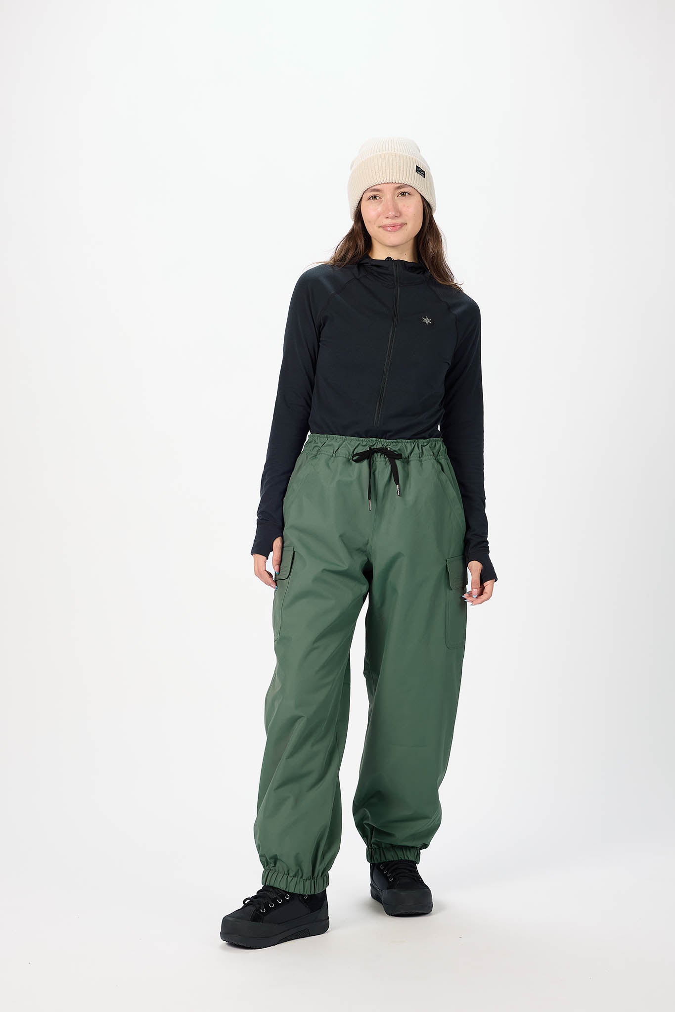 Person wearing a black long-sleeve top and green cargo pants on a white background