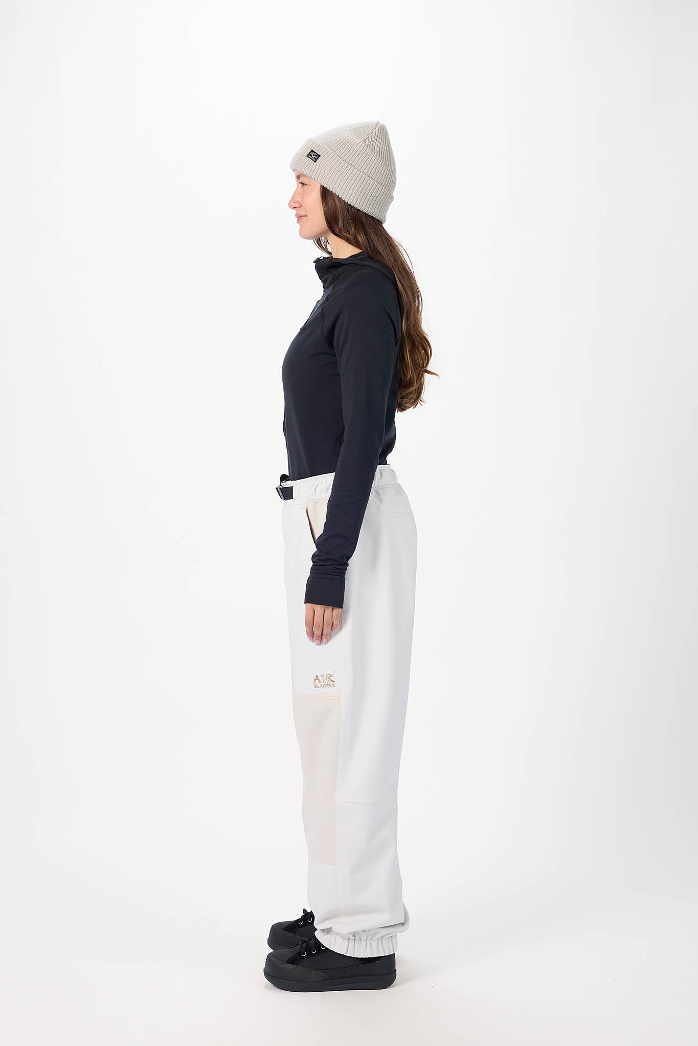 Person wearing a black top, white pants, and a gray beanie on a white background