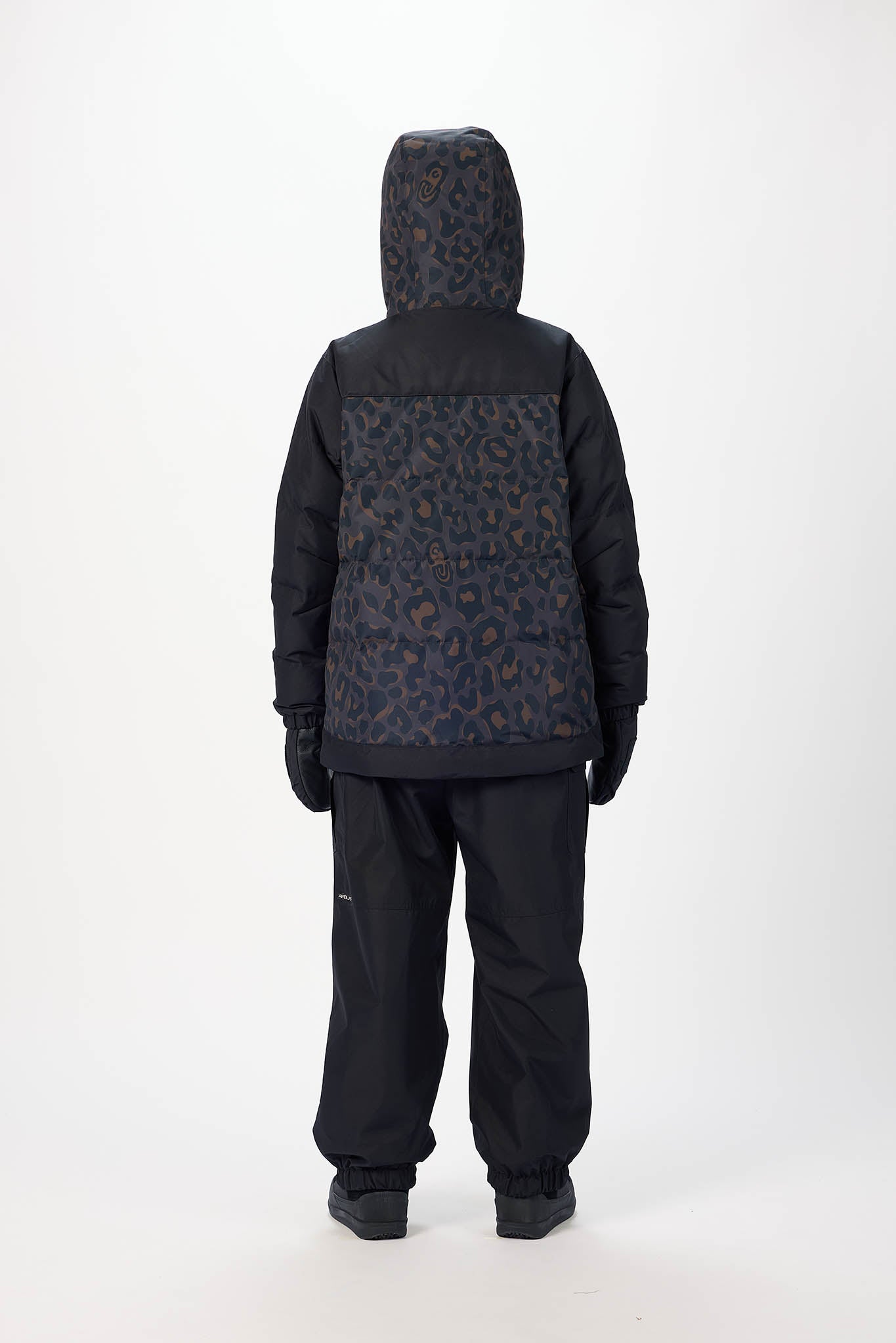 Person wearing a black and patterned jacket with matching pants on a white background