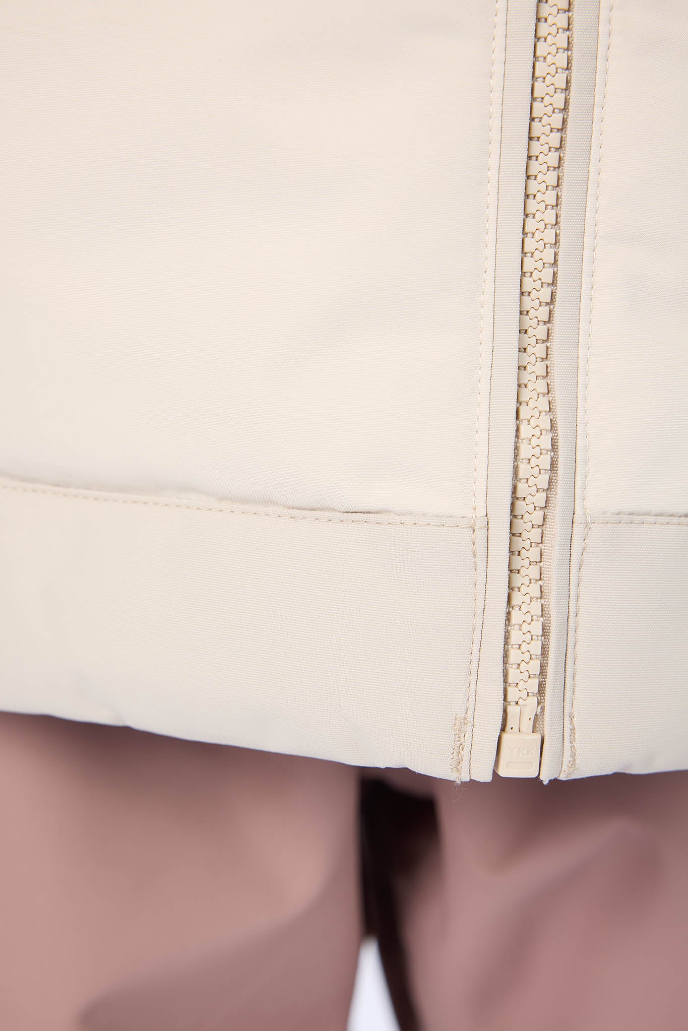 Close-up of a beige zippered garment on a white background