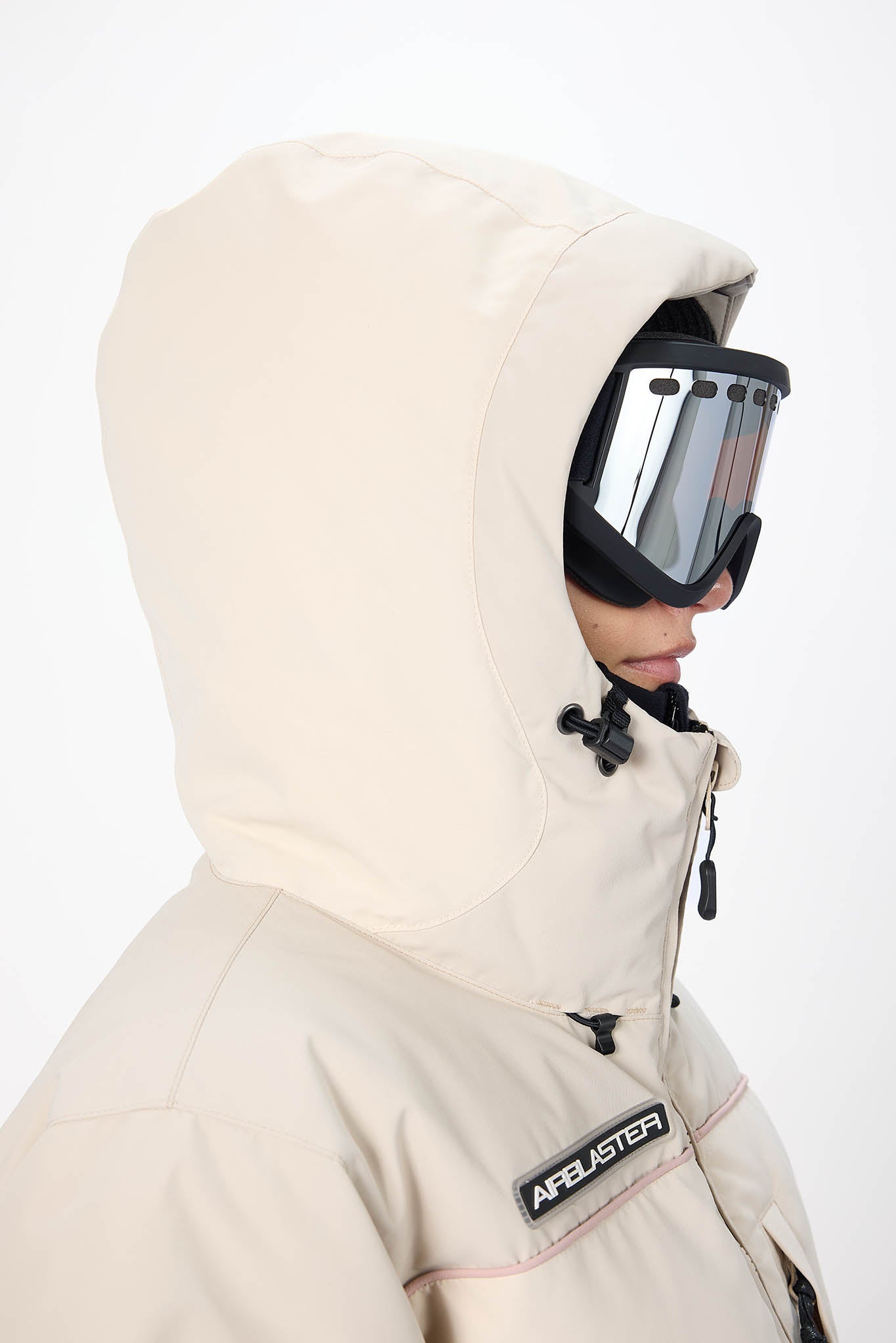 Person wearing a beige snowmobile suit with a visor and Apealster branding on a white background