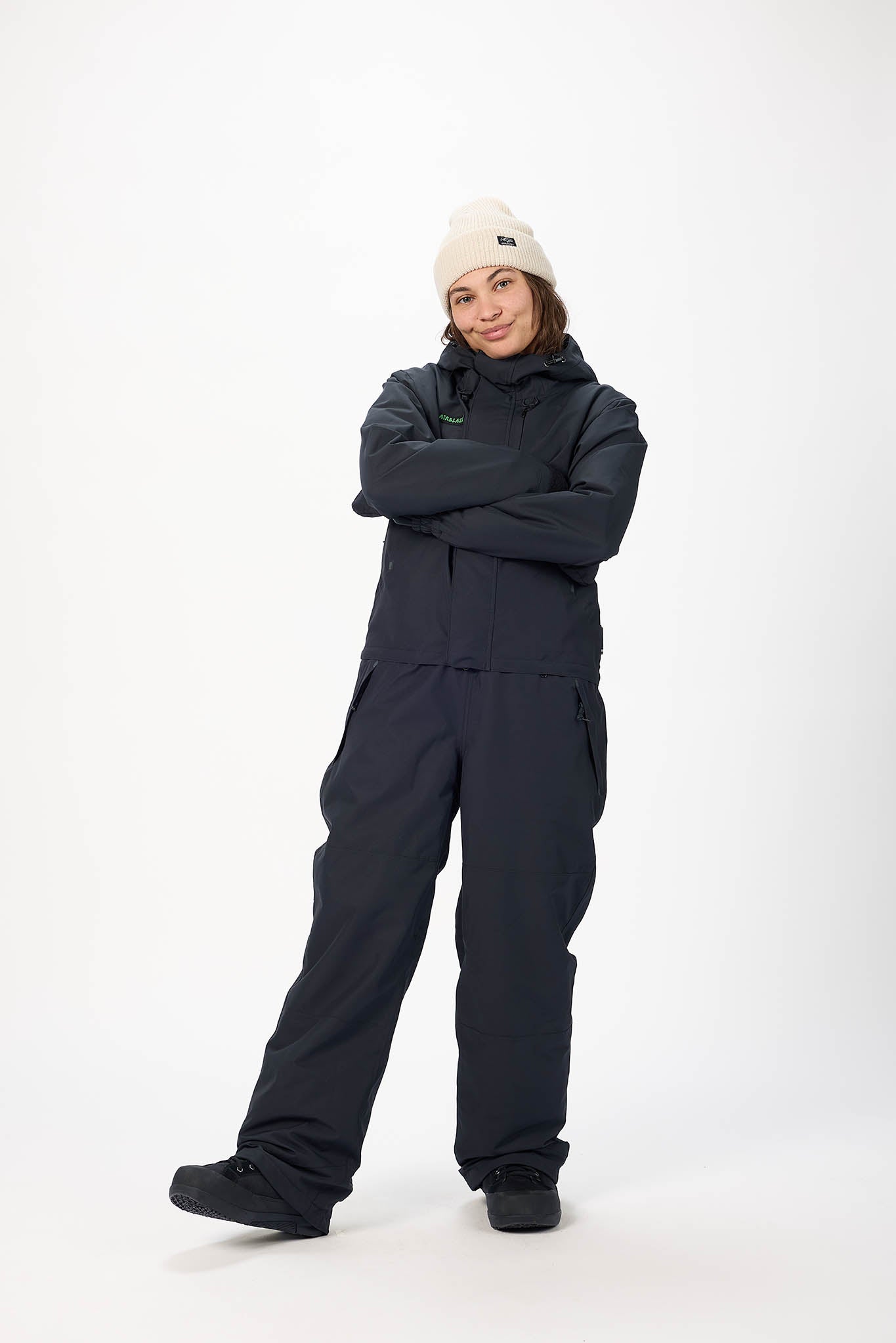 Person wearing a black snowsuit with a white beanie on a white background