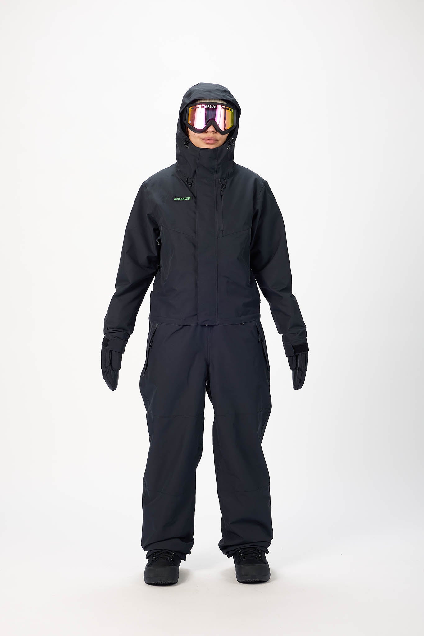 Person wearing a black snowmobile suit with goggles on a white background