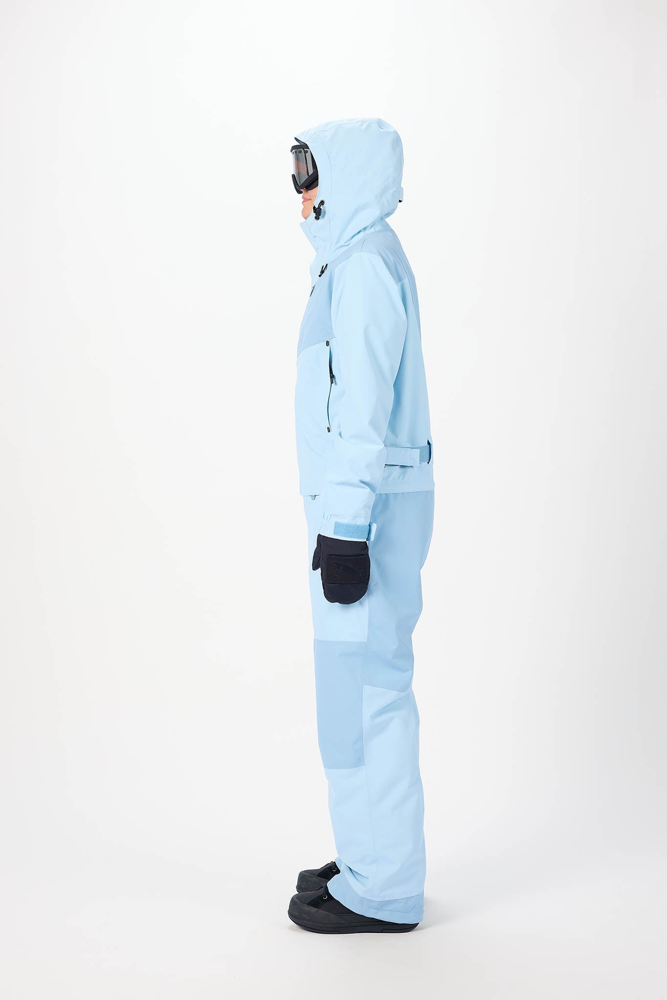 in side profile Person wearing a light blue snowsuit on a white background