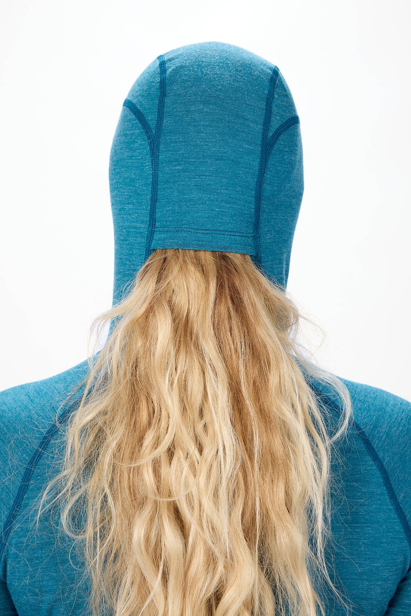 Back view of a person wearing a teal blue athletic hood with long blonde hair visible underneath, against a plain white background.
