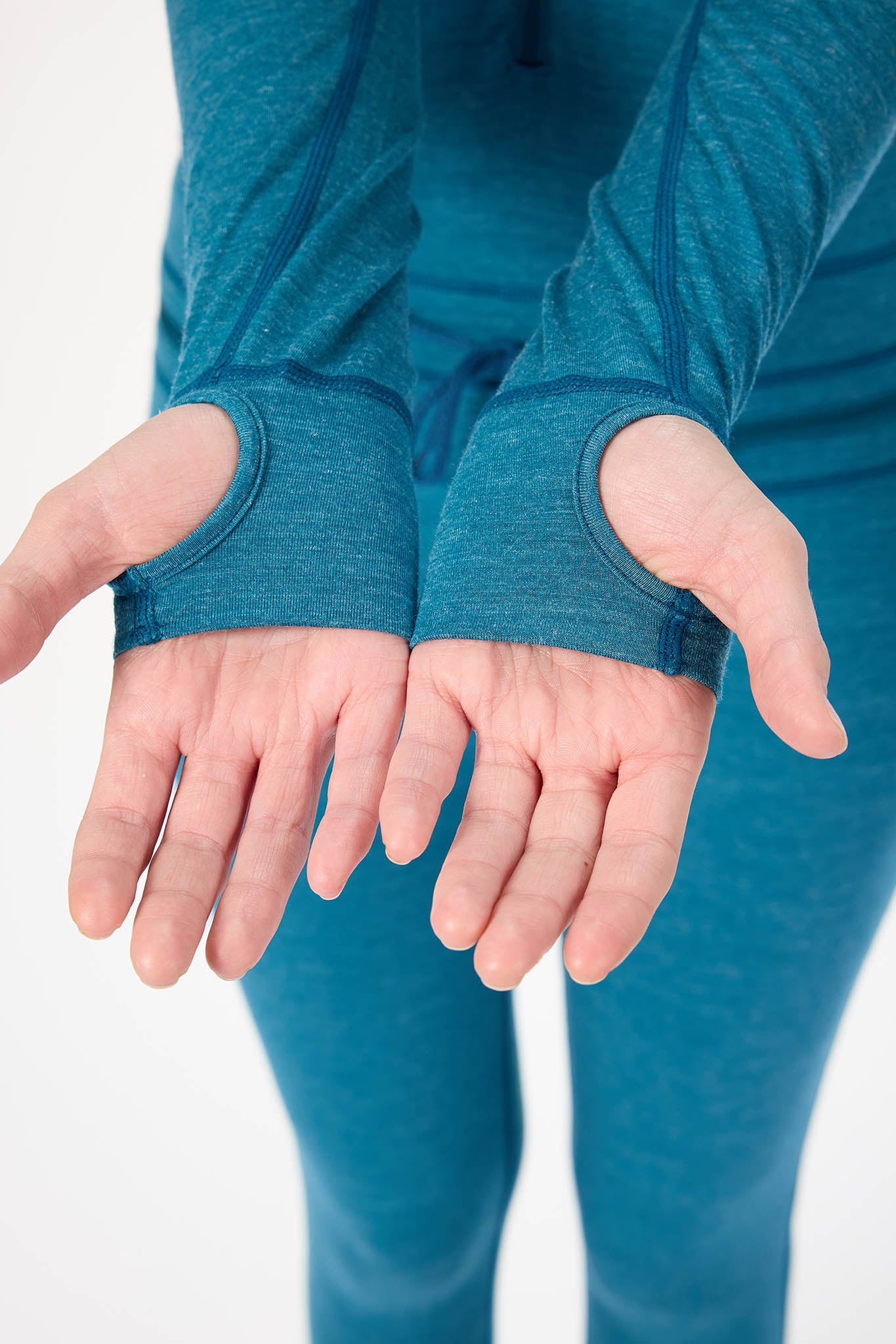 A close-up of a person's hands wearing teal blue fingerless wrist sleeves, paired with matching teal leggings, against a plain white background.