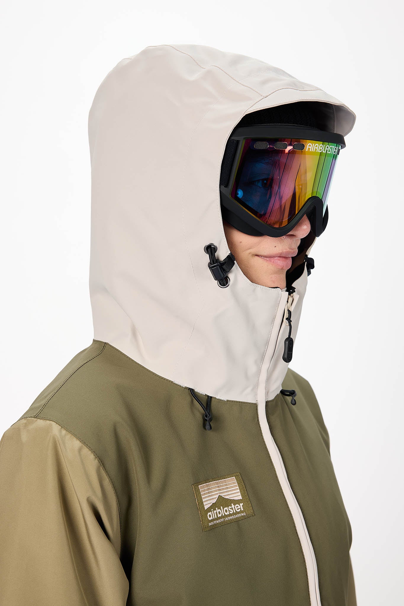 Person wearing a beige hooded jacket with a rainbow ski goggle on a white background