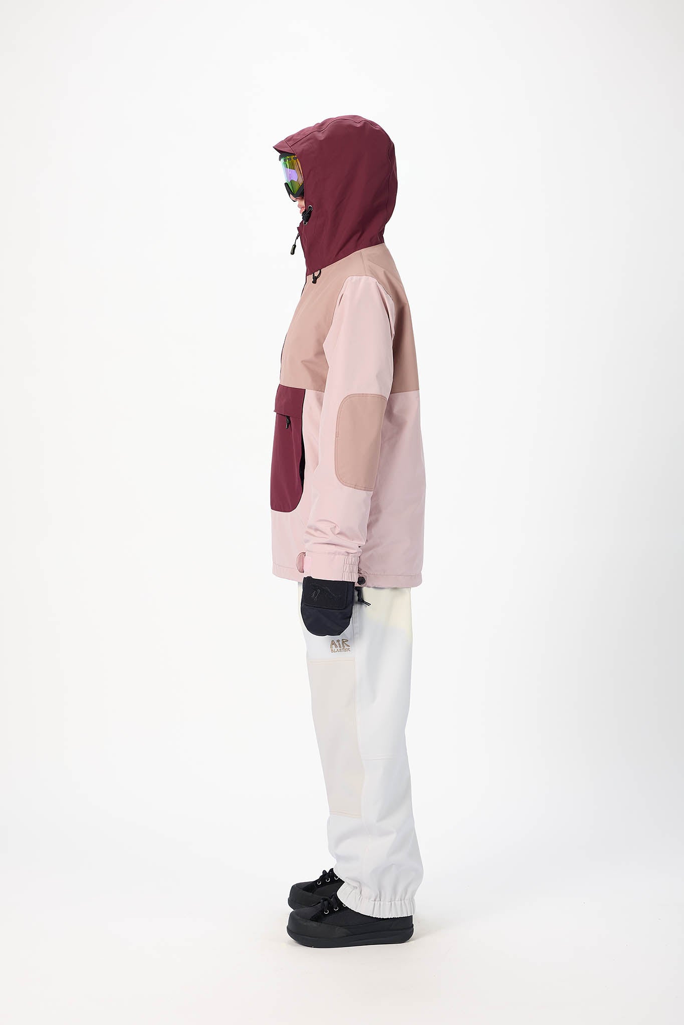 Person wearing a pink and maroon hoodie with white pants on a white background