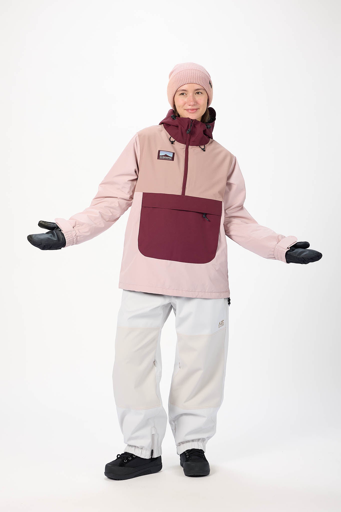 Person wearing a pink jacket with a maroon pocket, white pants, and black gloves on a white background