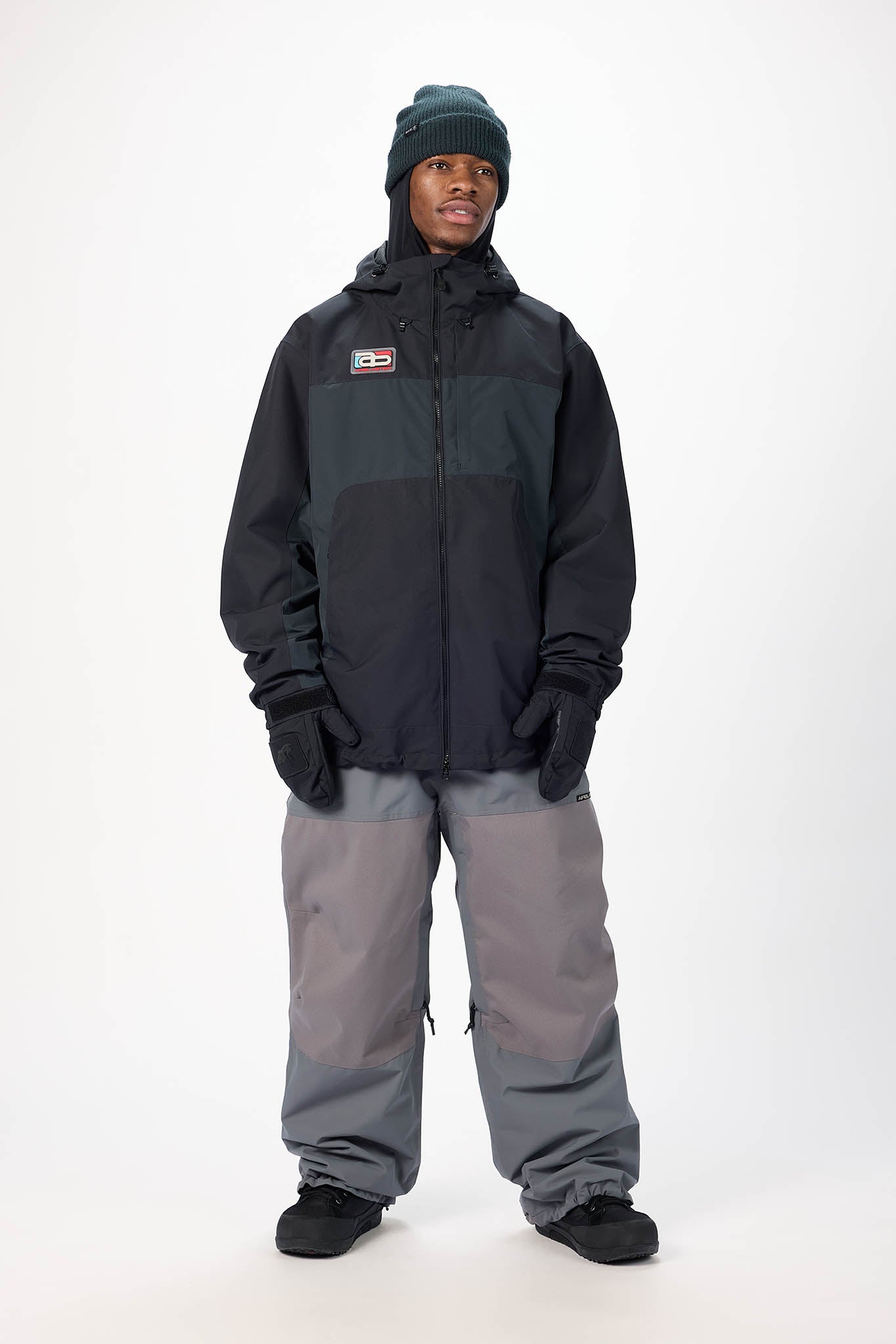Person wearing a black jacket and gray pants on a white background