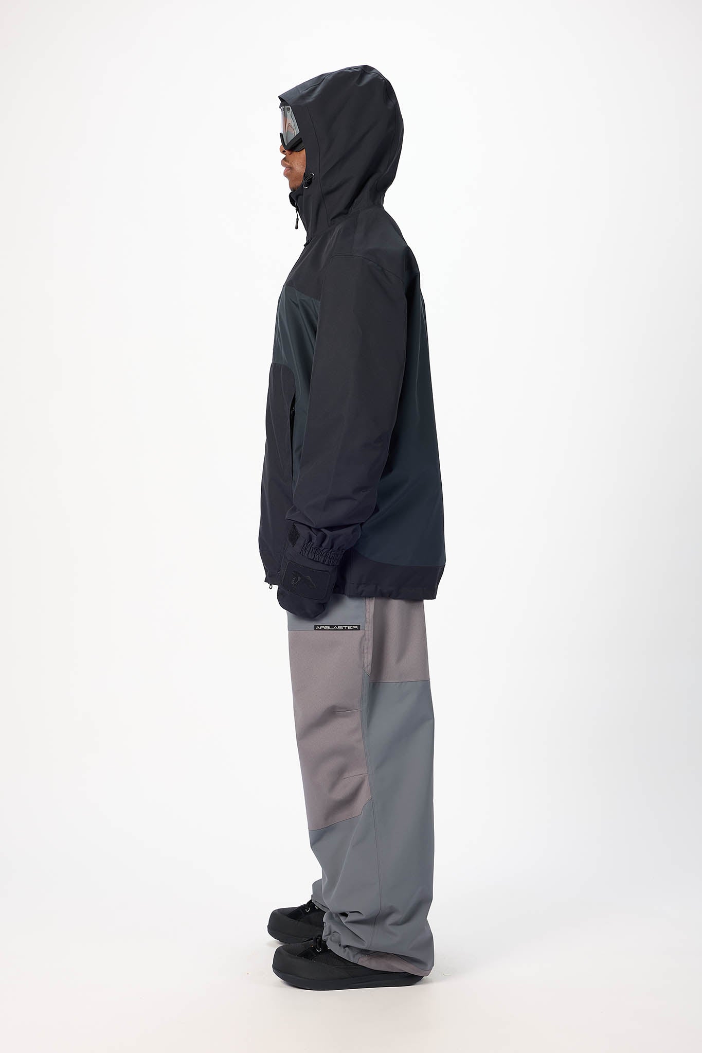 Person wearing a dark gray hoodie and light gray pants on a white background