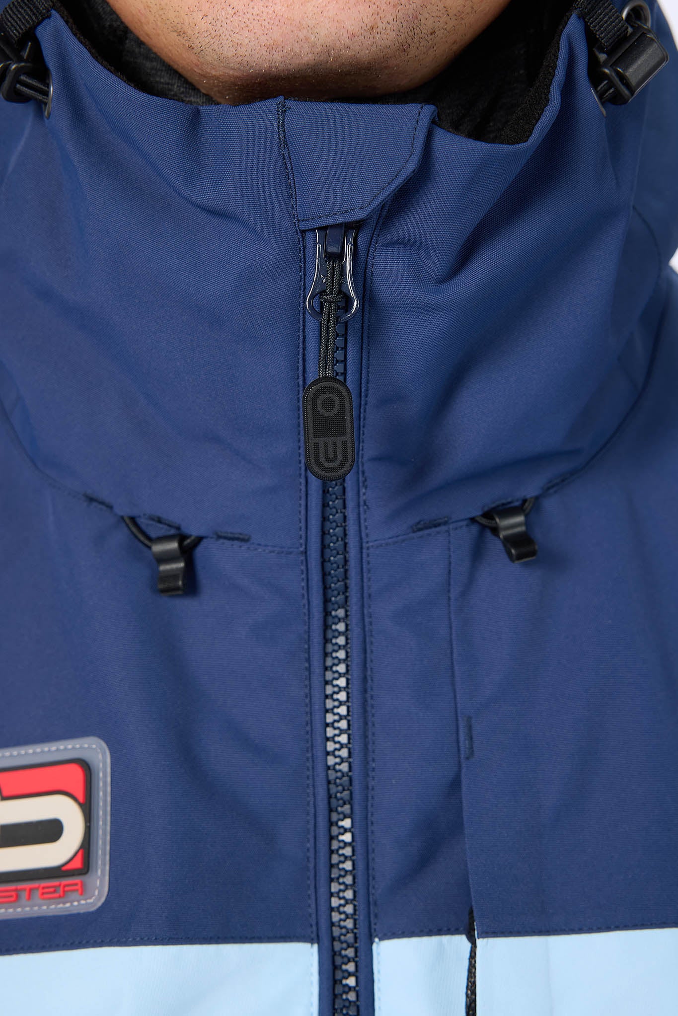 Close-up of a blue jacket with a brand logo on a white background