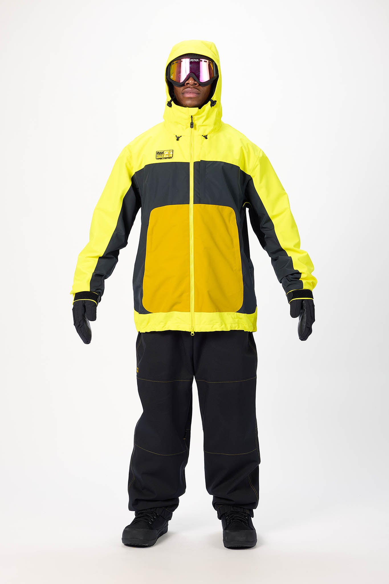 Person wearing a yellow and black snowsuit with goggles on a white background