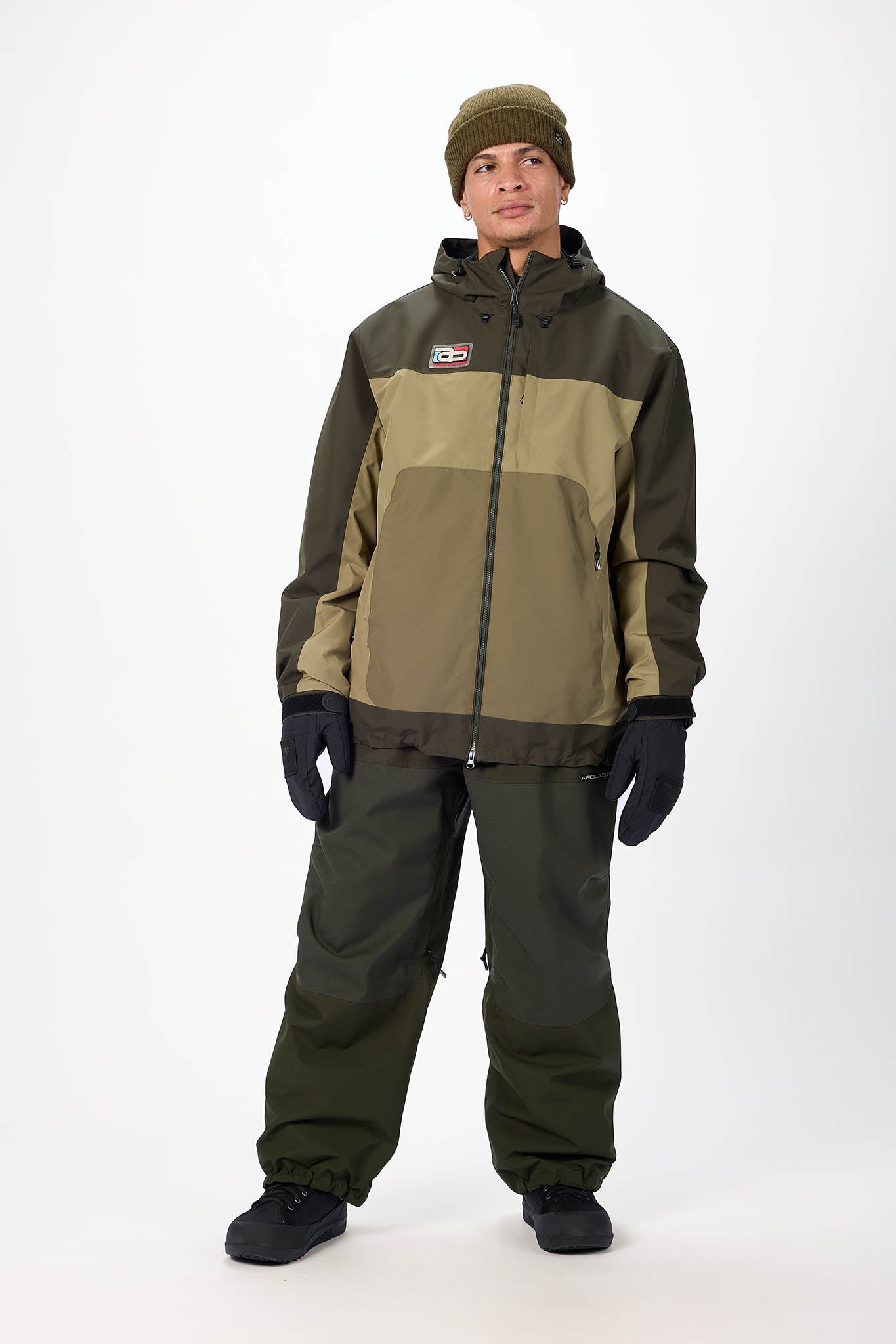 Person wearing a green and brown jacket with matching pants on a white background