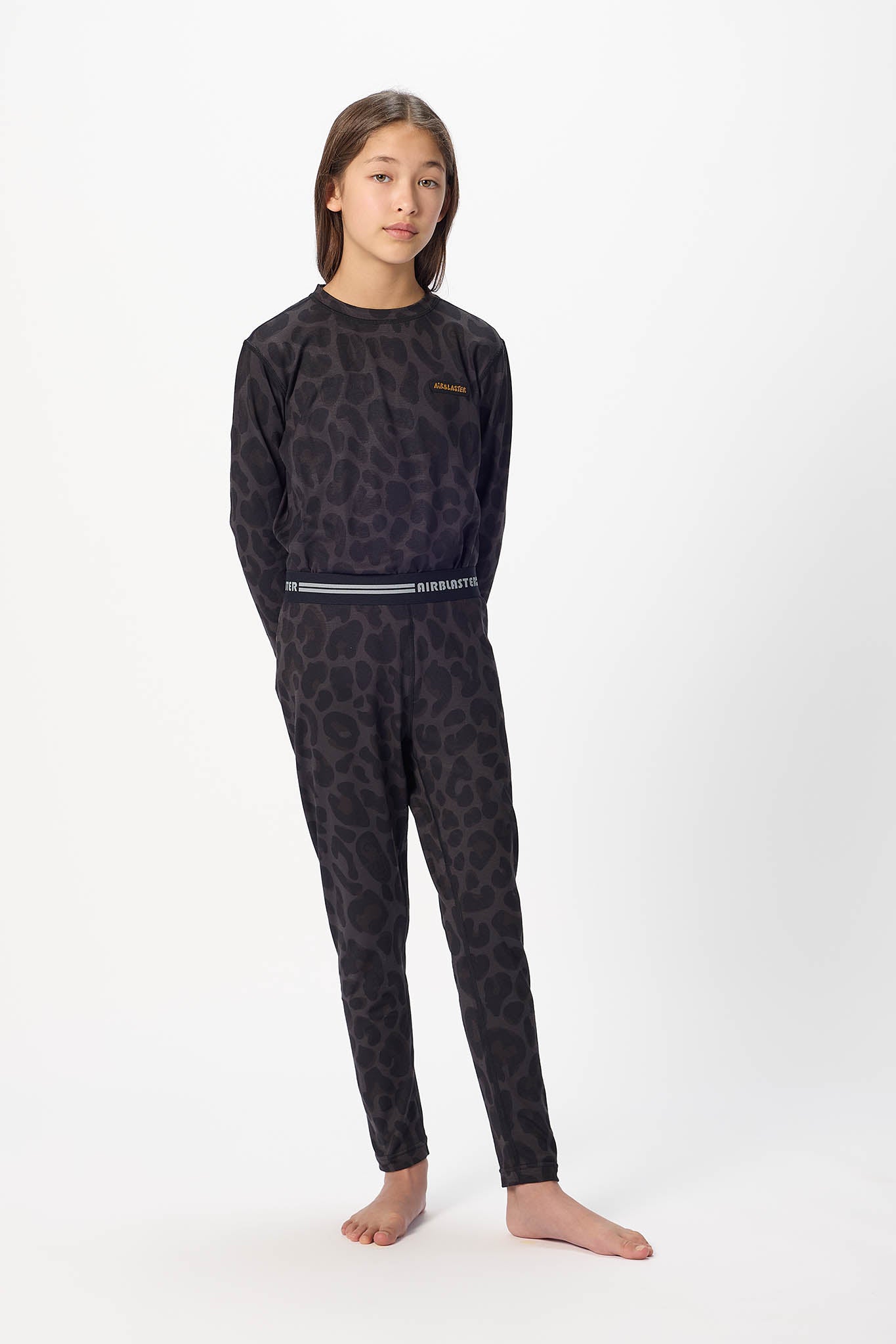 Youth standing center frame, looking away wearing Black leopard, youth base layer bottoms with white background.