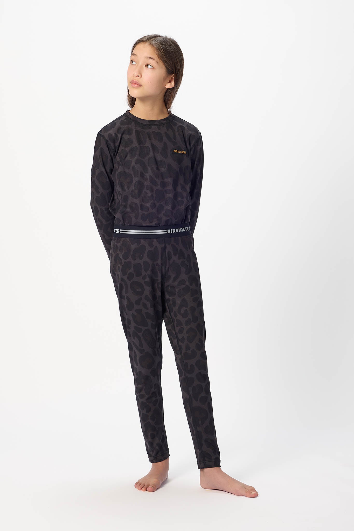 Youth standing center frame, looking away wearing Black leopard, youth base layer bottoms with white background.