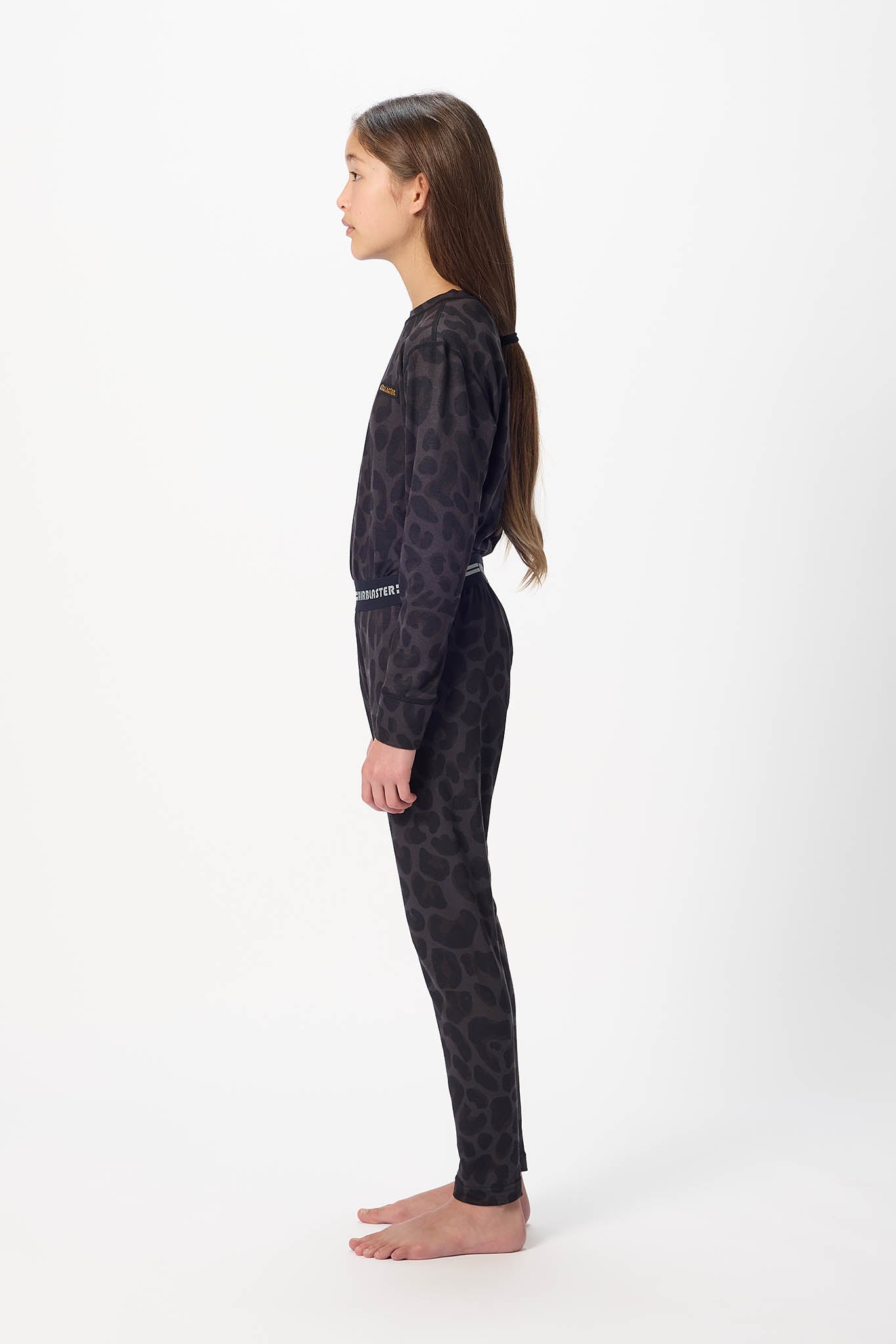 Youth model wearing black with Black leopard base layer bottoms,standing sideways.