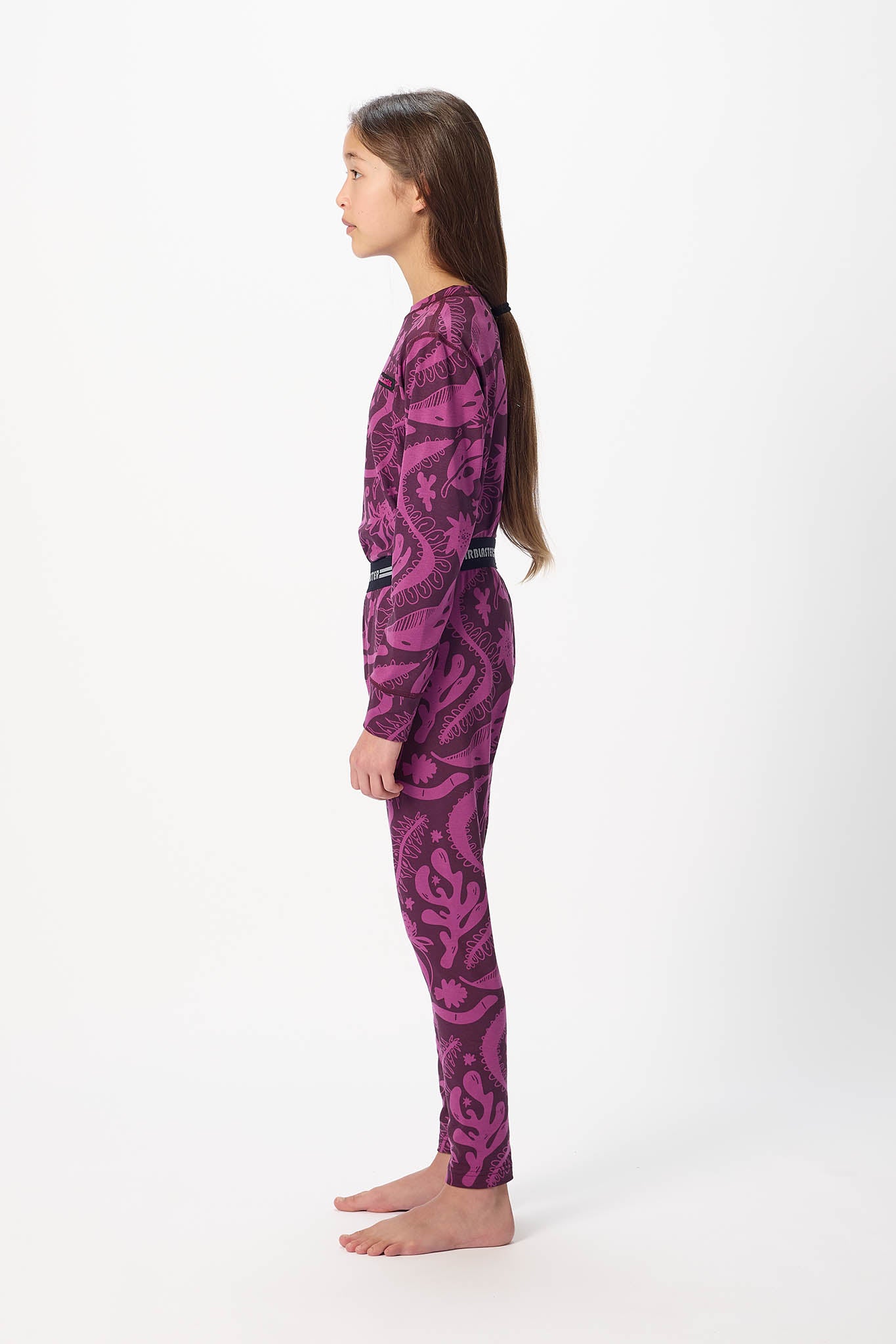 Youth model wearing black with Plum Earth life base layer bottoms,standing sideways