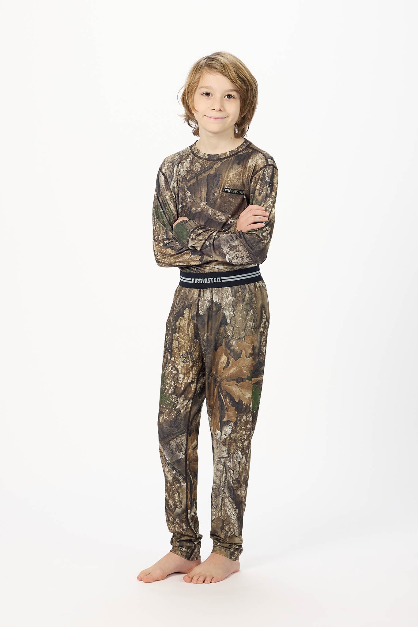 Youth standing center frame, wearing youth base RealTree Camouflage layer bottoms with white background.