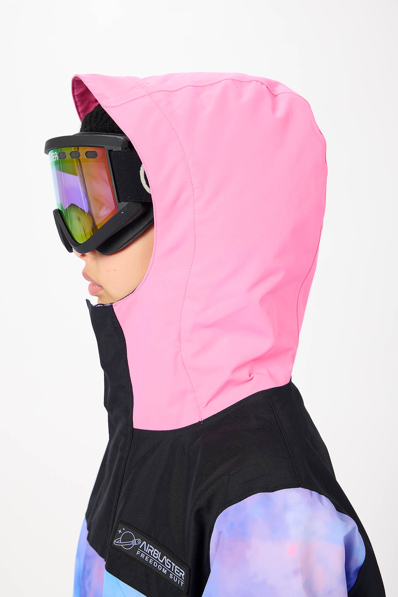 A child wearing a pink hooded ski jacket with black and purple sections, black ski goggles, and a white logo on the chest, shown against a plain white background.