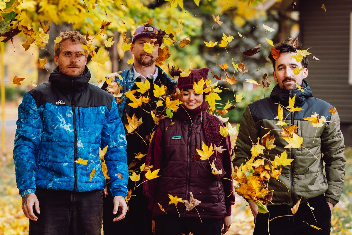 a group of people standing with a pile of yellow leaves cascading down in front of them. 