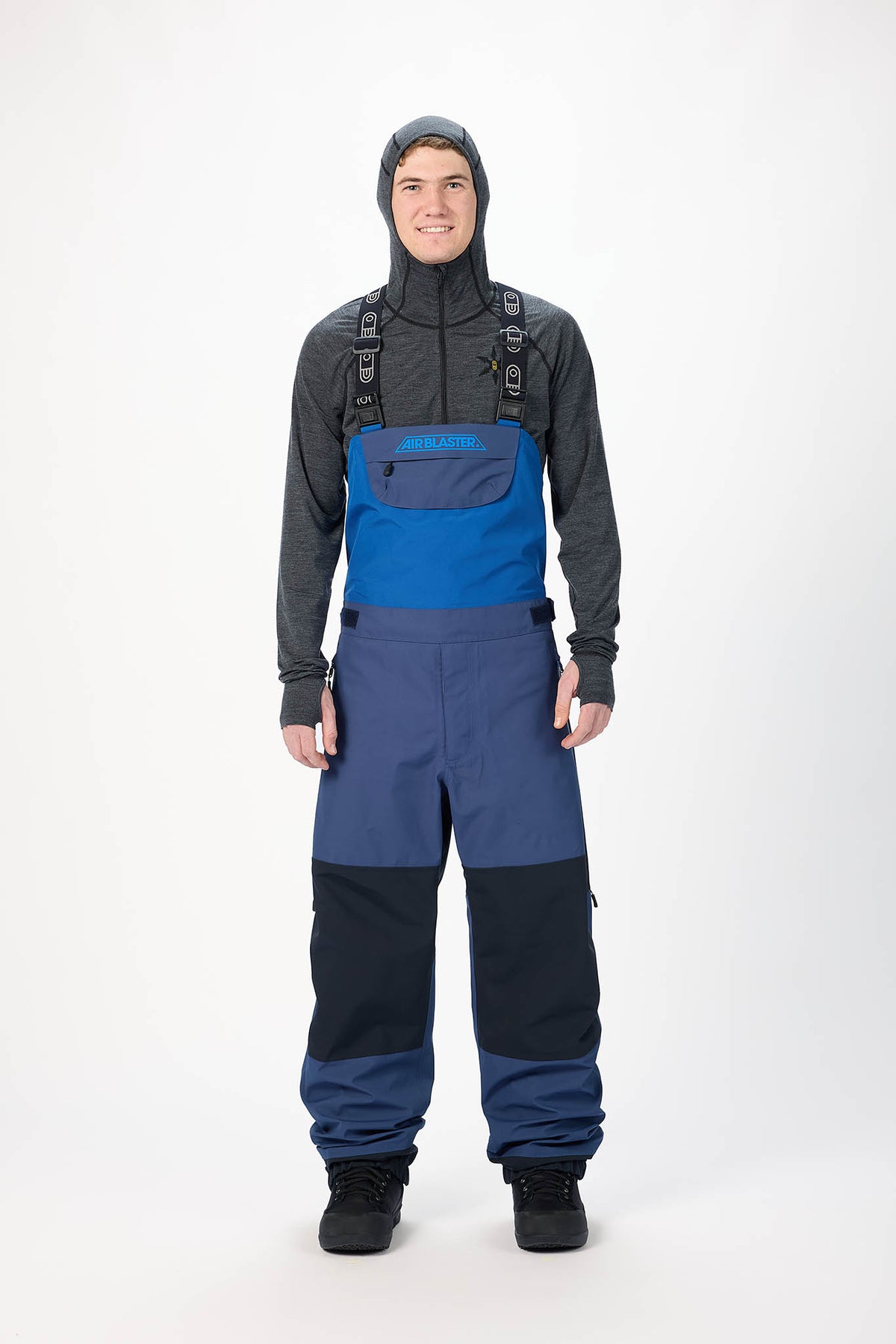 Person wearing a blue snowmobile suit with a black jacket on a white background