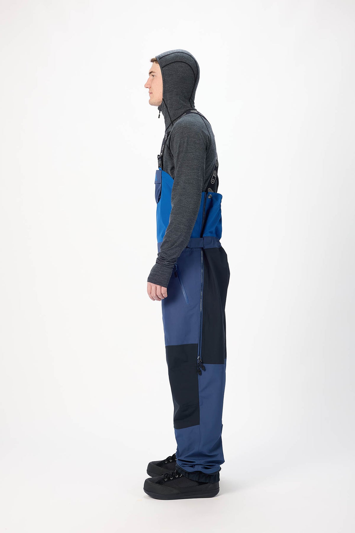 Person wearing blue and black snow pants with a hood on a white background