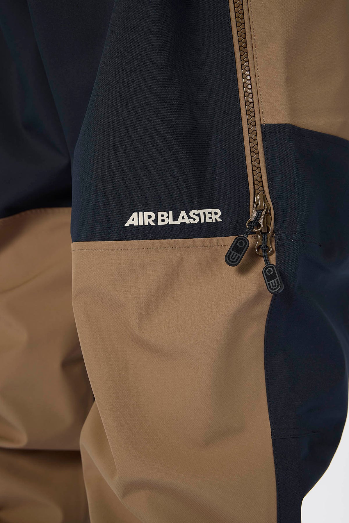 Close-up of a jacket with 'AIR BLASTER' branding on a beige and navy background