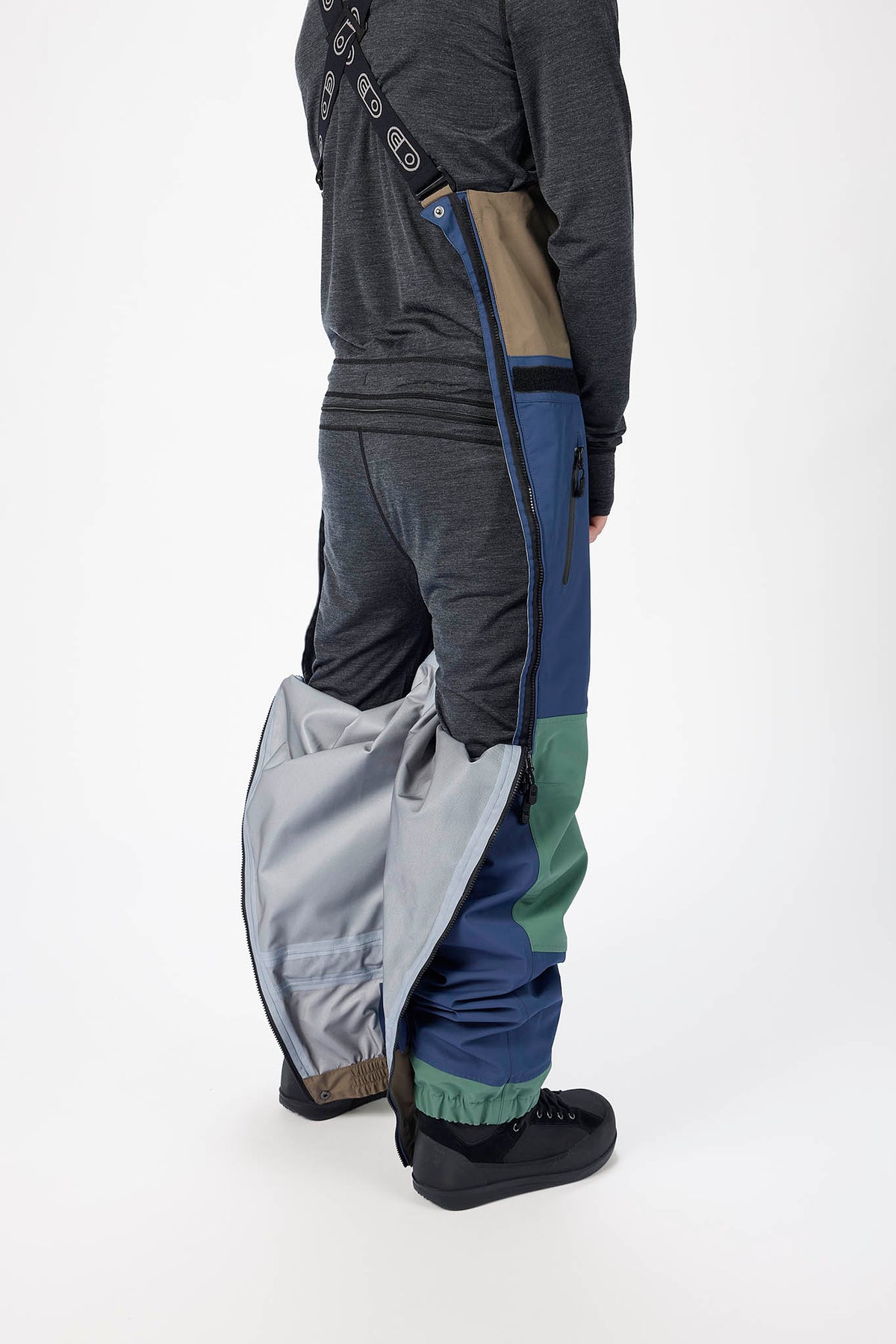 Person wearing a dark gray jacket, gray pants, and black boots on a white background