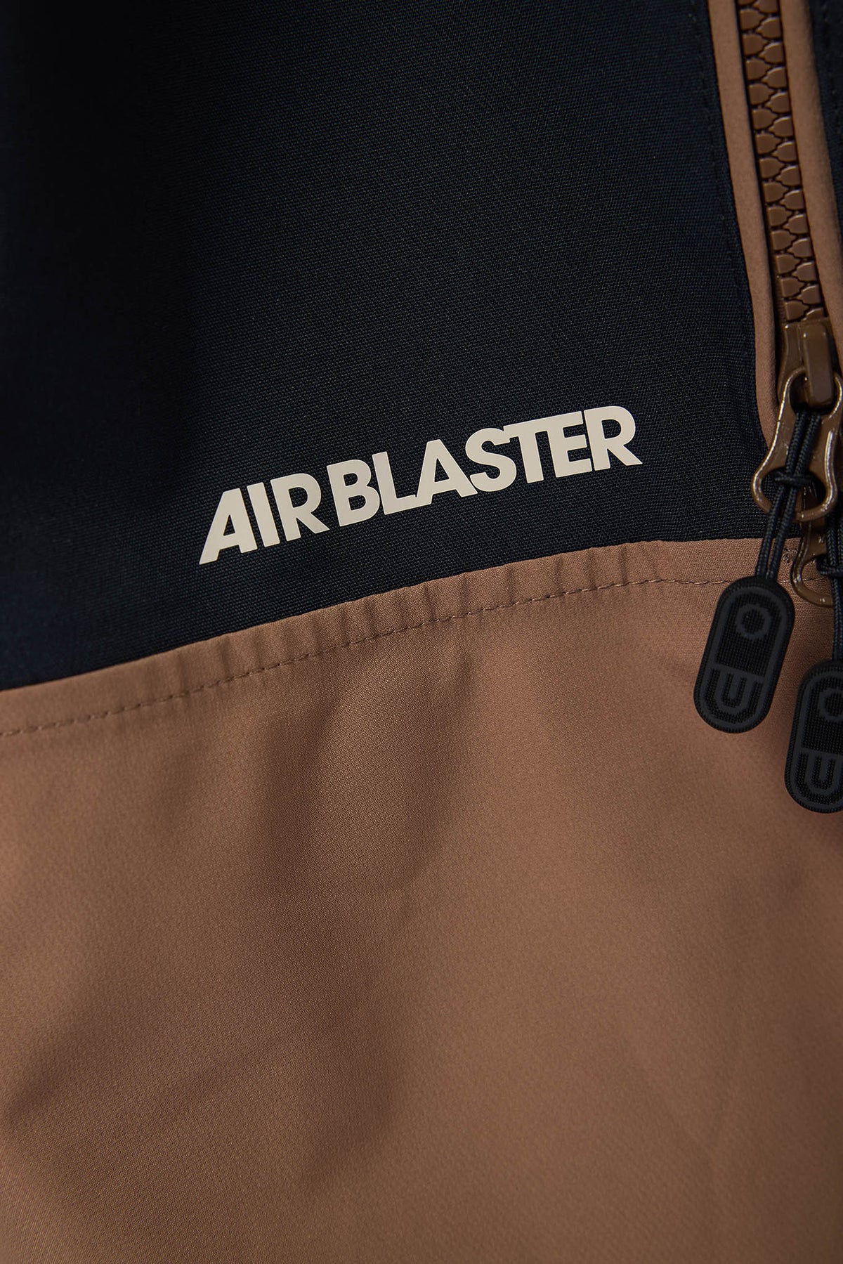 Close-up of a brown jacket with 'AIR BLASTER' branding on a black background.