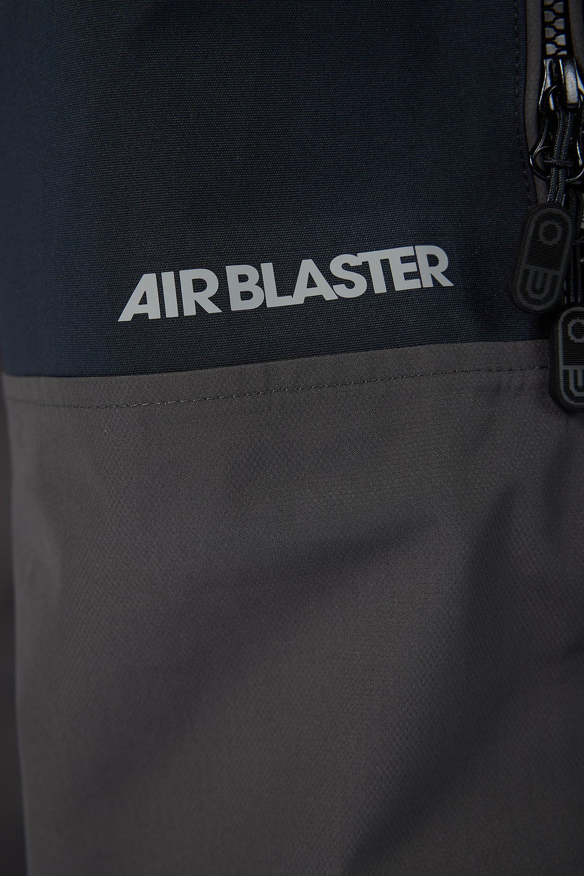 Close-up of a black jacket with 'AIR BLASTER' branding on a dark background