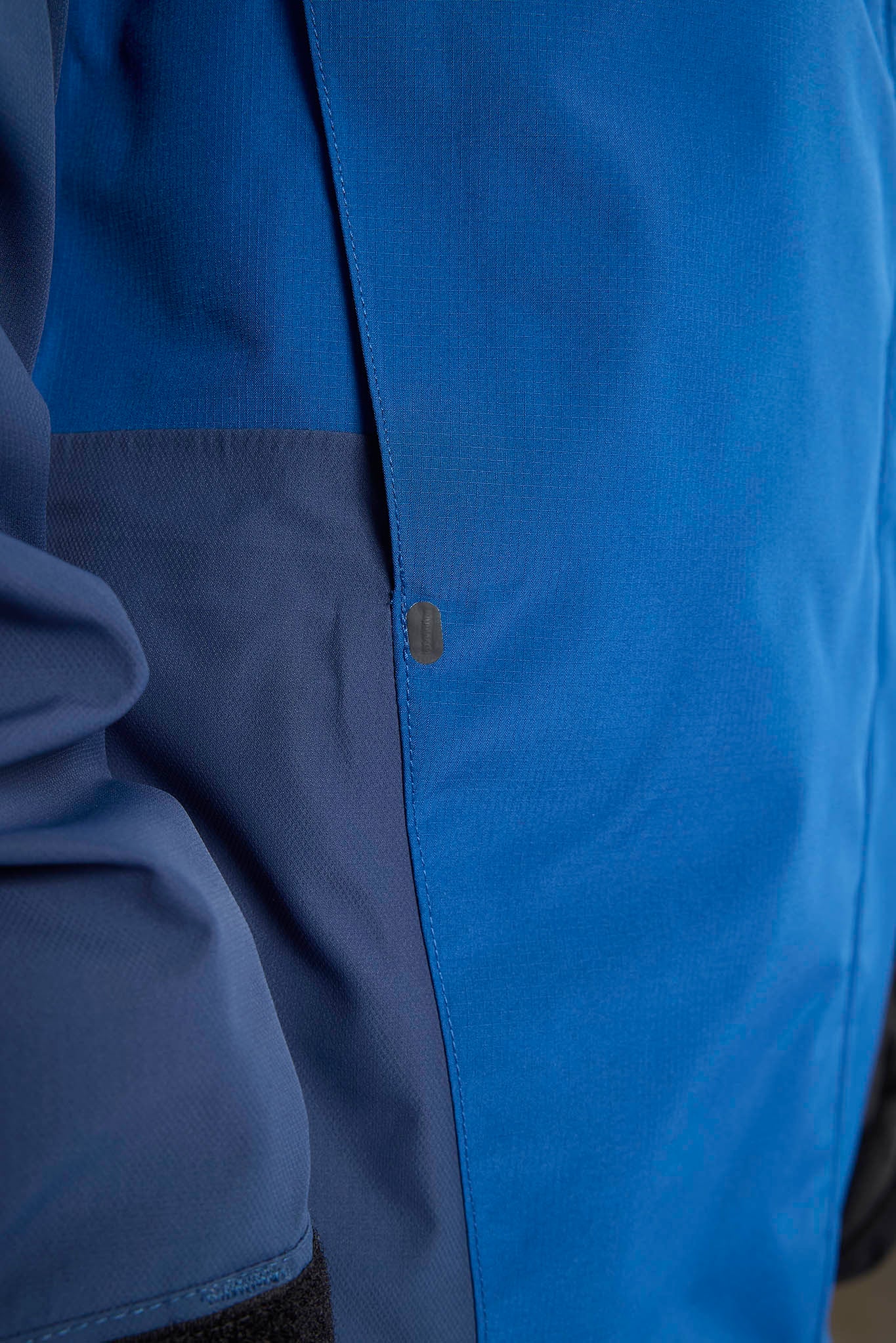 Close-up of a blue jacket with a brand logo on a blurred background