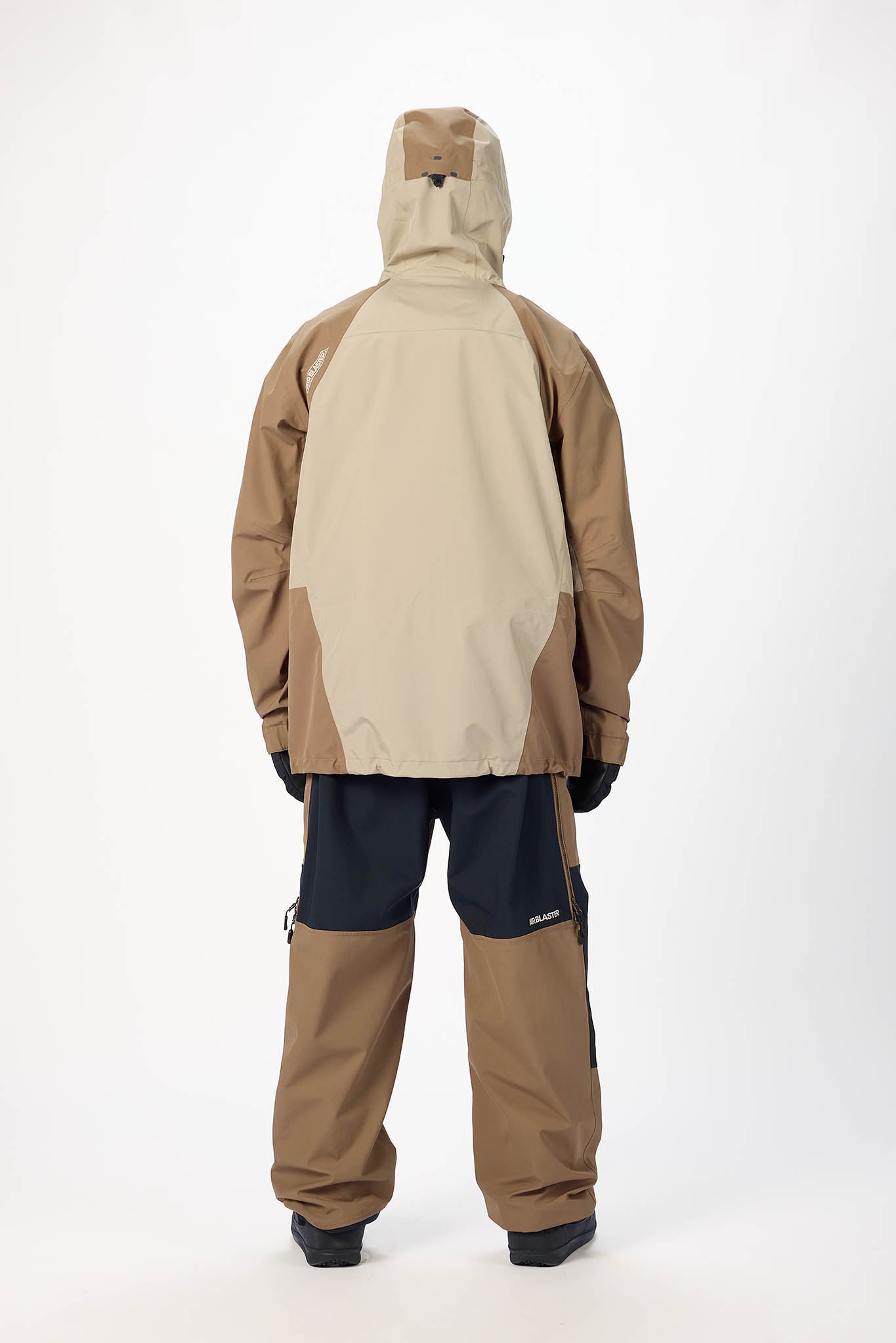 Person wearing a beige and black snowsuit on a white background
