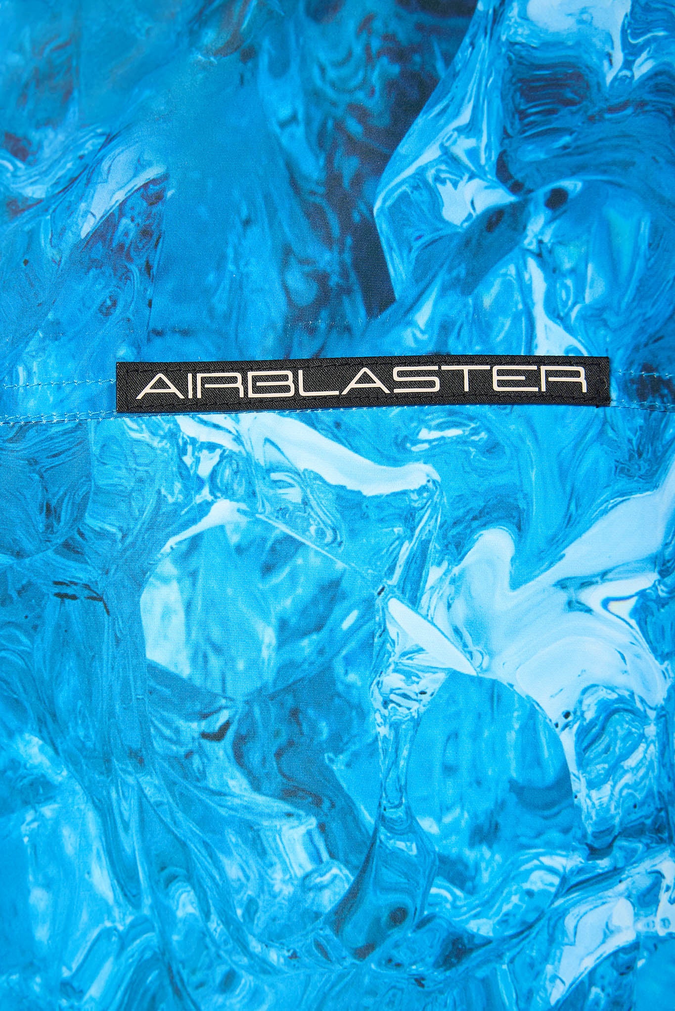 A close-up of a bright blue textured material with a black horizontal label reading AIRBLASTER across the center.