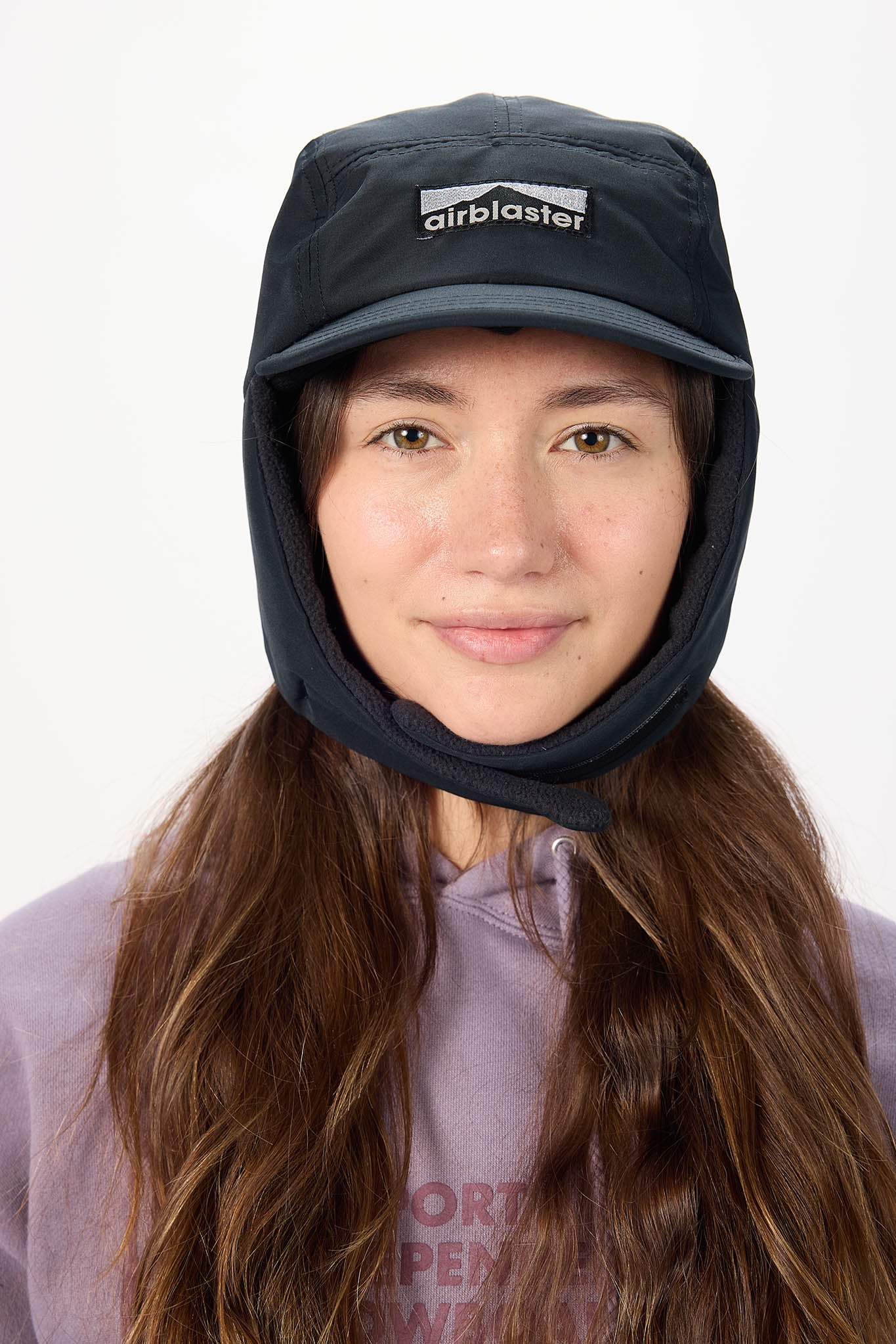 A woman wearing a black Airblaster ear flap hat with the flaps over the ear