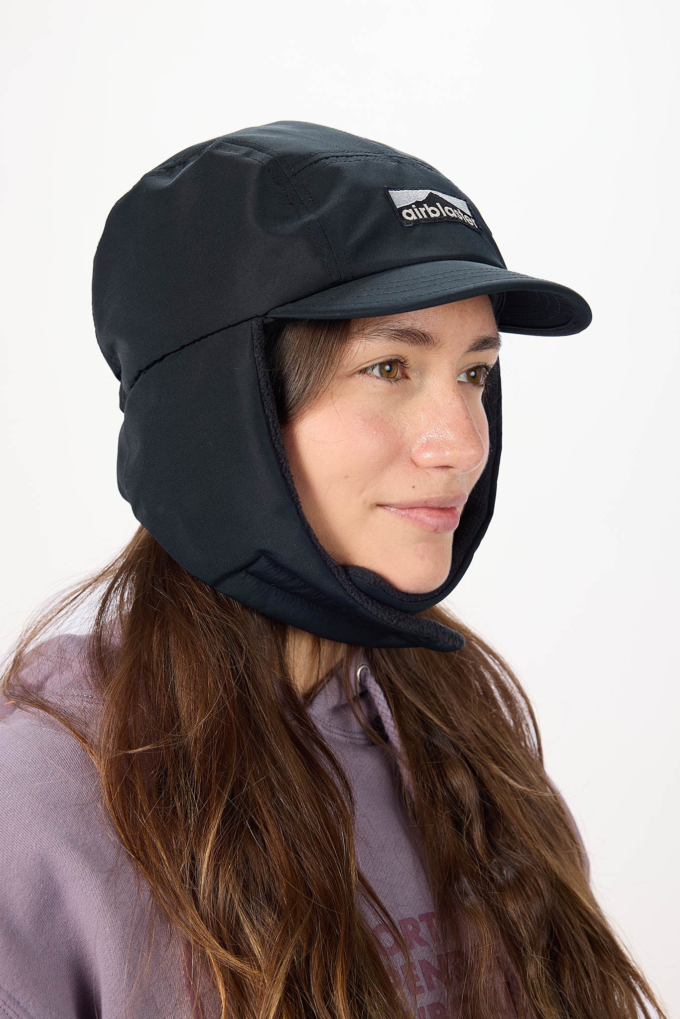 A woman in profile wearing a black outdoor sun hat with a built-in neck flap and visor, set against a plain white background.