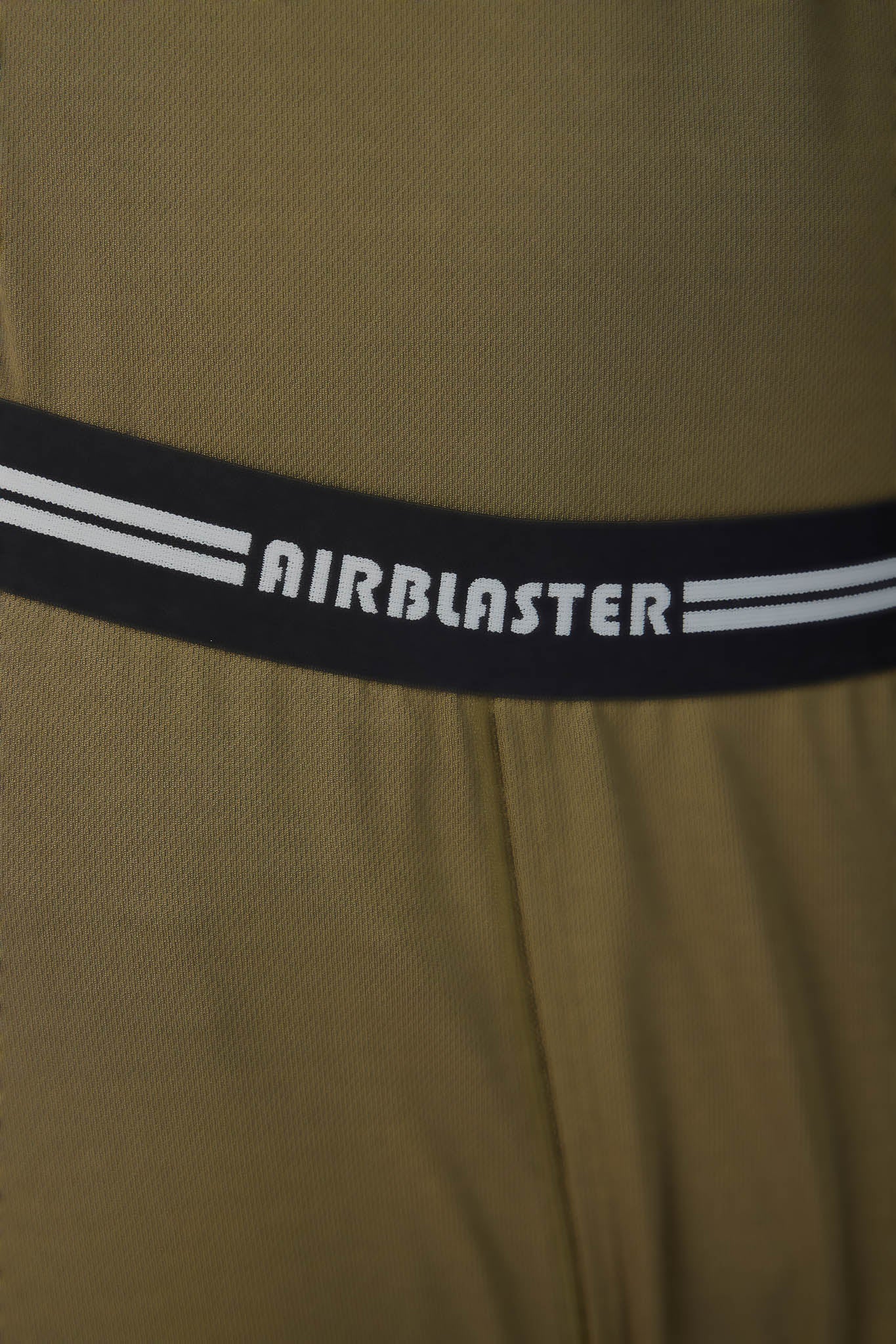 Close-up of a textured olive green garment with a black elastic waistband featuring the brand name 'AIRBLASTER' in white text and two white stripes.