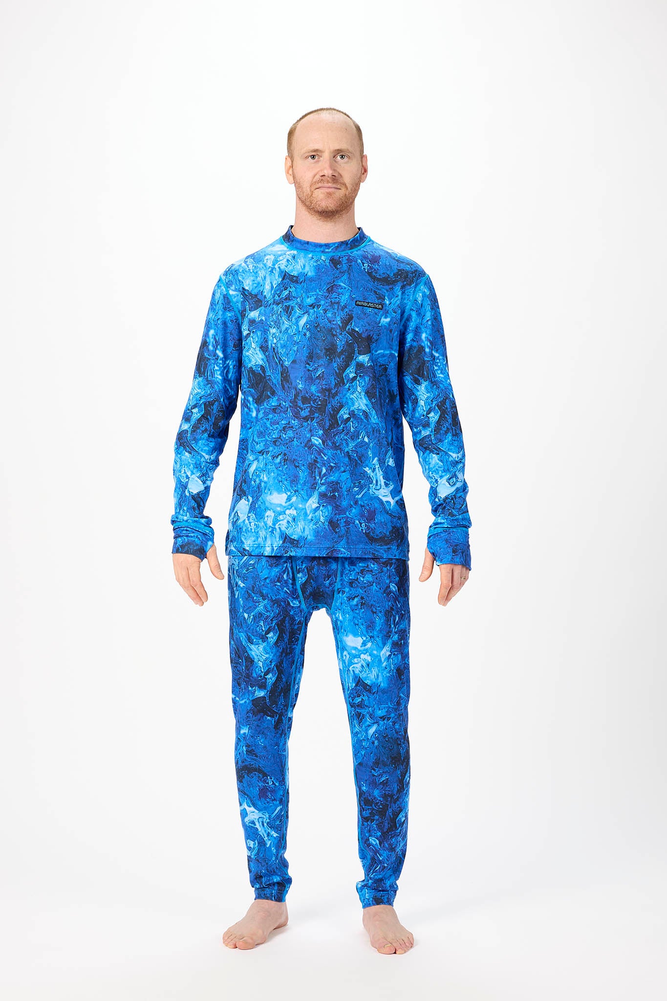 A man modeling a matching two-piece pajama set with a blue and navy abstract watercolor pattern, standing against a plain white studio background.
