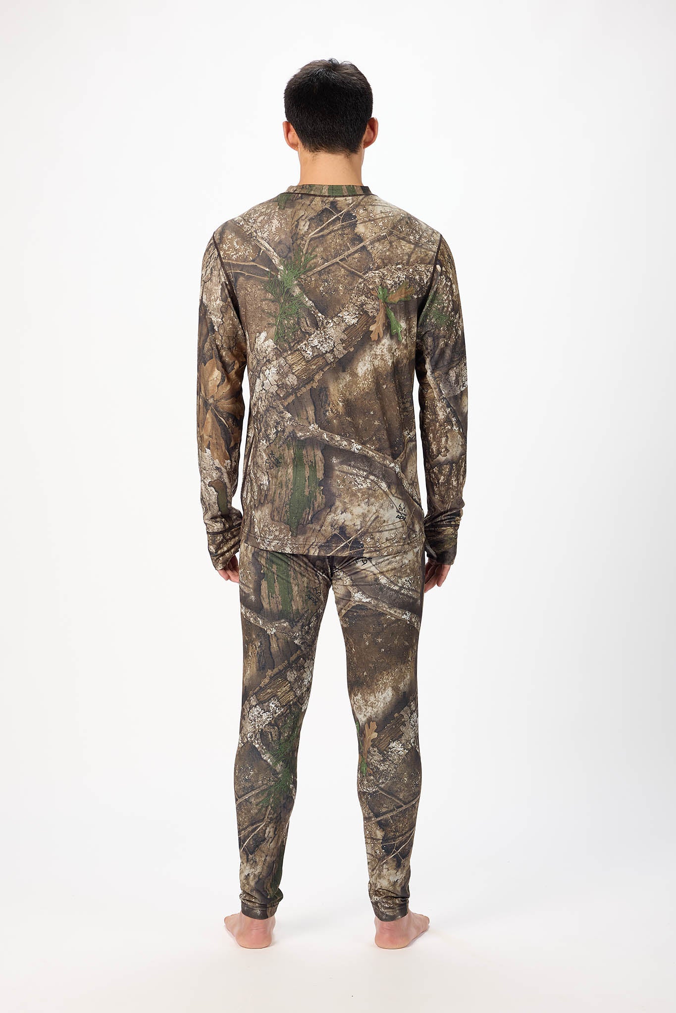 A man viewed from behind wearing a long-sleeve camouflage shirt and matching camouflage pants against a plain white studio background.