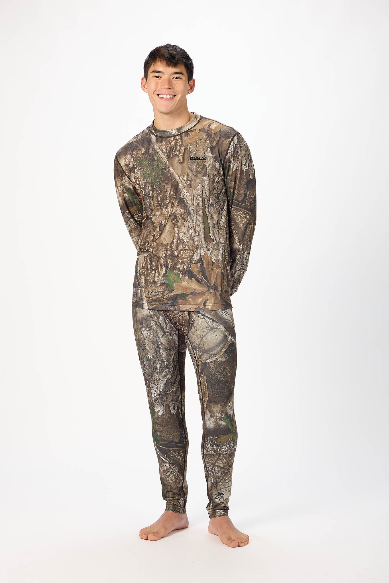 A man modeling a matching camouflage long-sleeve shirt and pants set against a plain white studio background.