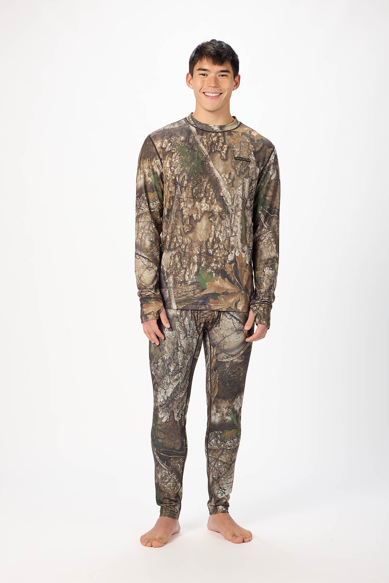 A man modeling a matching camouflage long-sleeve shirt and pants set against a plain white studio background.